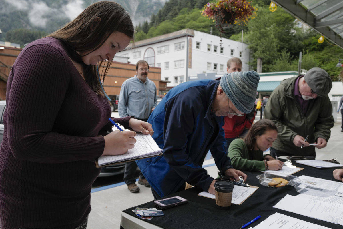 In this file photo from Aug. 1, 2019, Monika Kunat, left, signs an application petition to recall Gov. Mike Dunleavy with others at the Planet Alaska Gallery in downtown Juneau.                                 Michael Penn | 
Juneau Empire