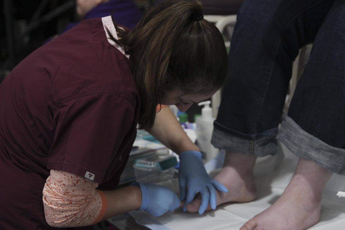 Lia Sickoria, a registered nurse at Bartlett Regional Hospital, cleans a guest’s feet at the Juneau Coalition for Housing and Homelessness’ 9th annual Homeless Connect event at the Juneau Arts and Culture Center Wednesday. (Michael S. Lockett | Juneau Empire)