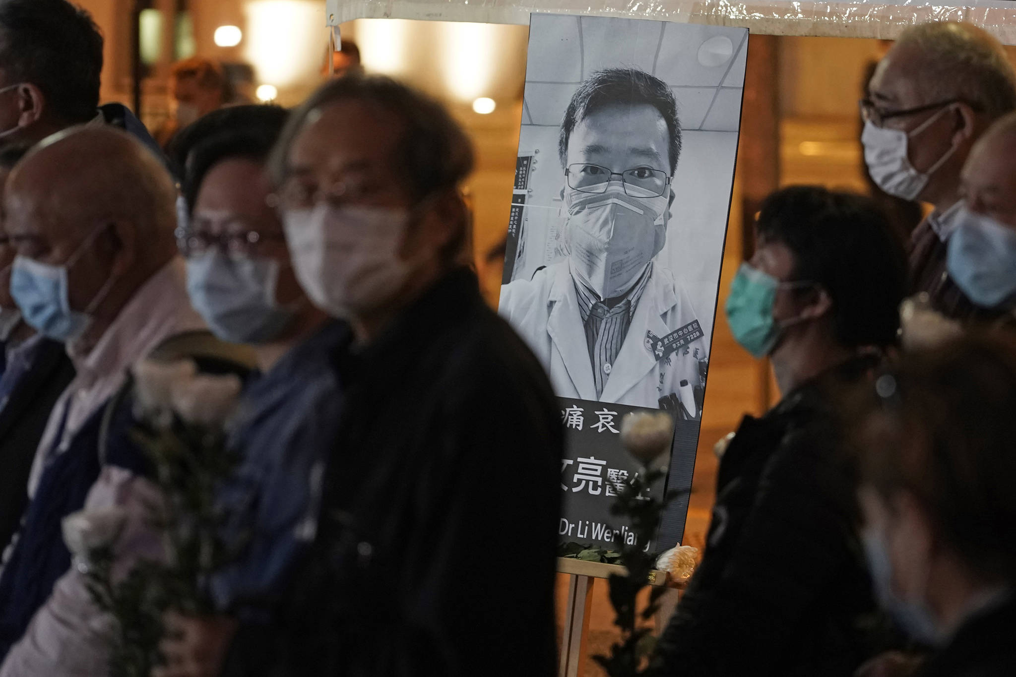 People wearing masks, attend a vigil for Chinese doctor Li Wenliang, in Hong Kong, Friday. The death of a young doctor who was reprimanded for warning about China’s new virus triggered an outpouring Friday of praise for him and fury that communist authorities put politics above public safety. (AP Photo | Kin Cheung)