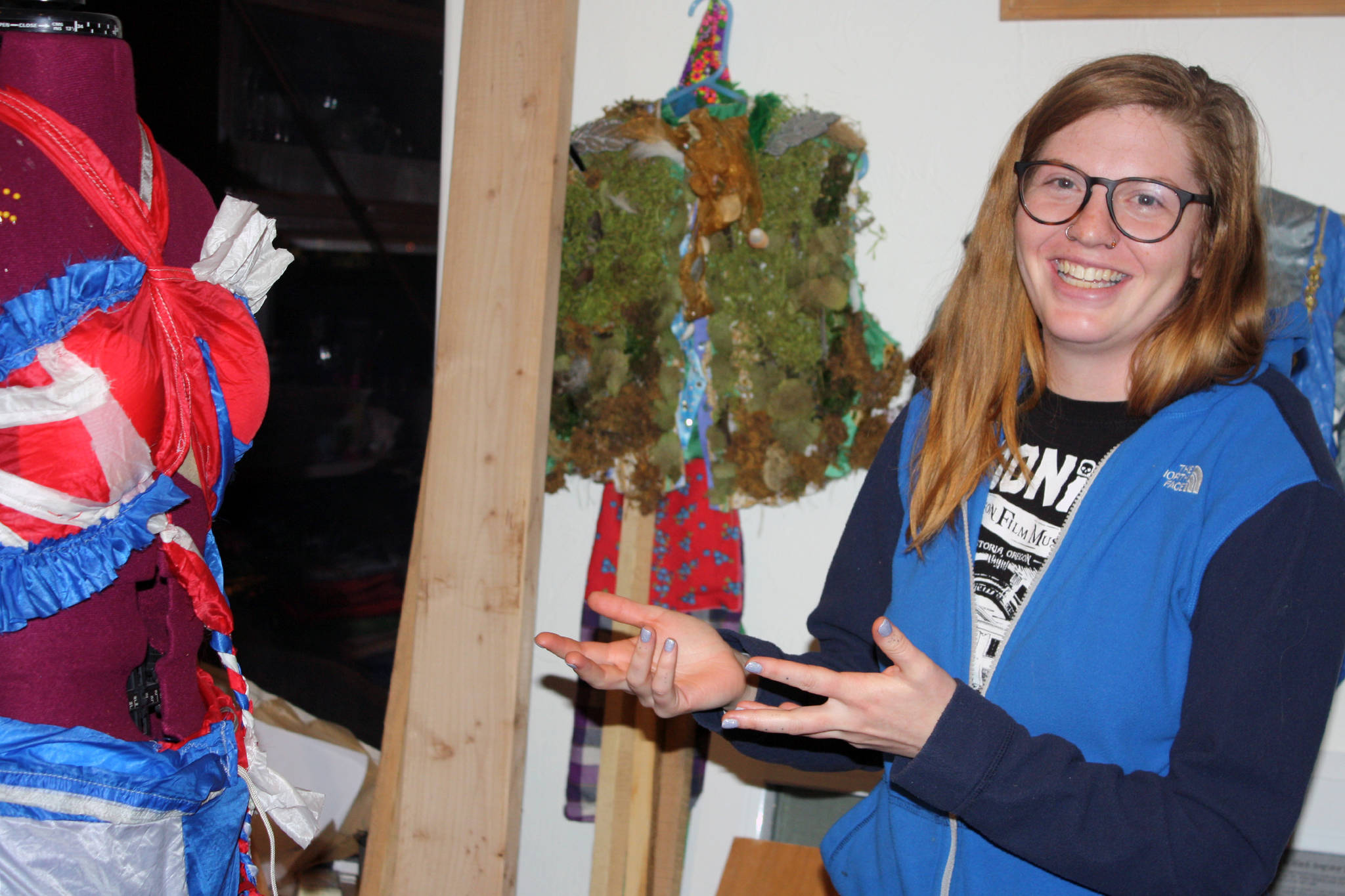 Keren GoldbergBelle gestures at her Wearable Art 2020: Joie de Vivre piece. “The theme is sort of Abba meets Chiquita Banana,” GoldbergBelle said. “That’s what this is.” Past Wearable Art pieces can be seen in the background. (Ben Hohenstatt | Capital City Weekly)