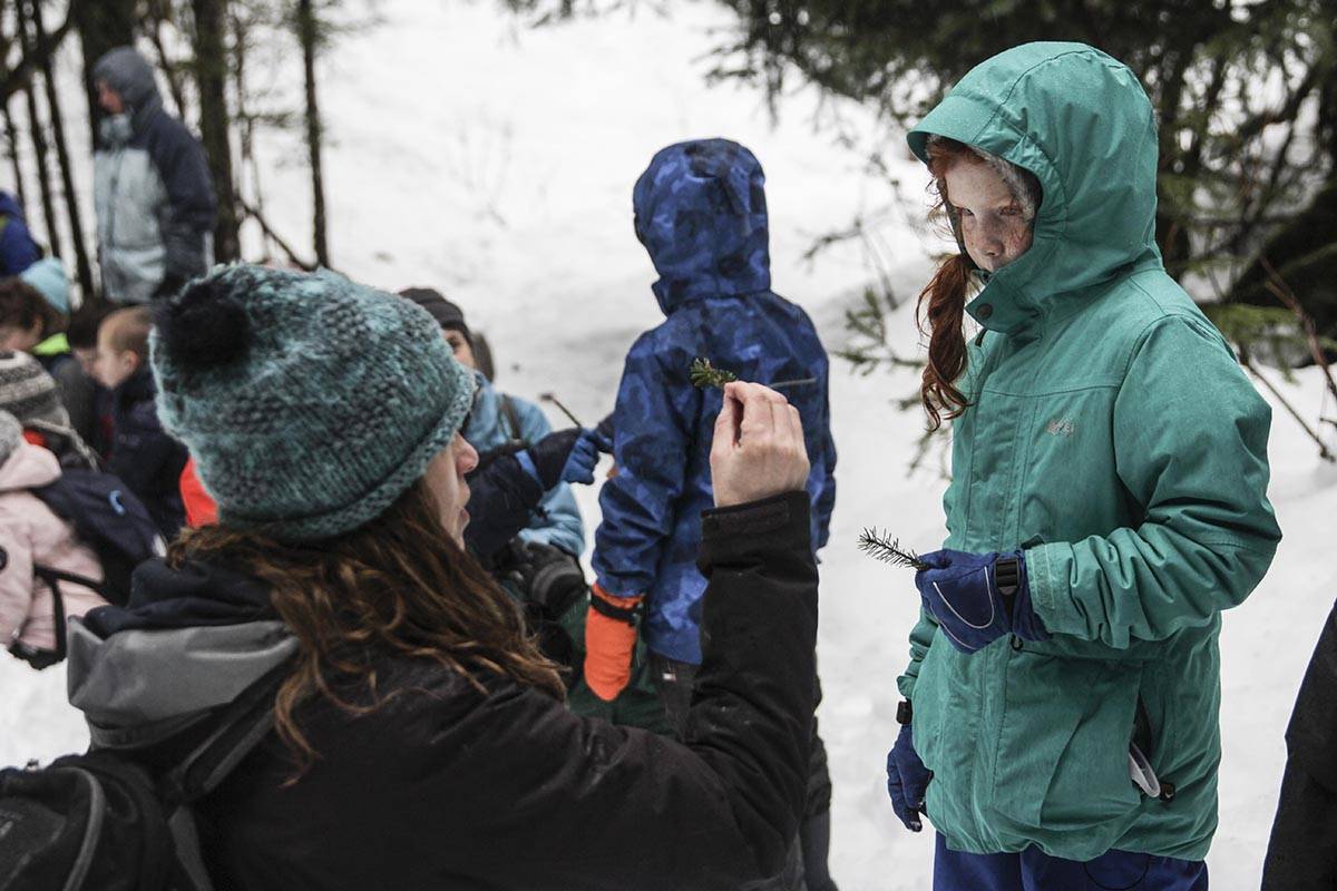 Discovery Southeast education coordinator Kelly Sorensen talks to a student from Harborview Elementary School about what feeds on the trees during a nature hike near the Mendenhall Glacier Visitor Center on Feb. 20, 2020. (Michael S. Lockett | Juneau Empire)