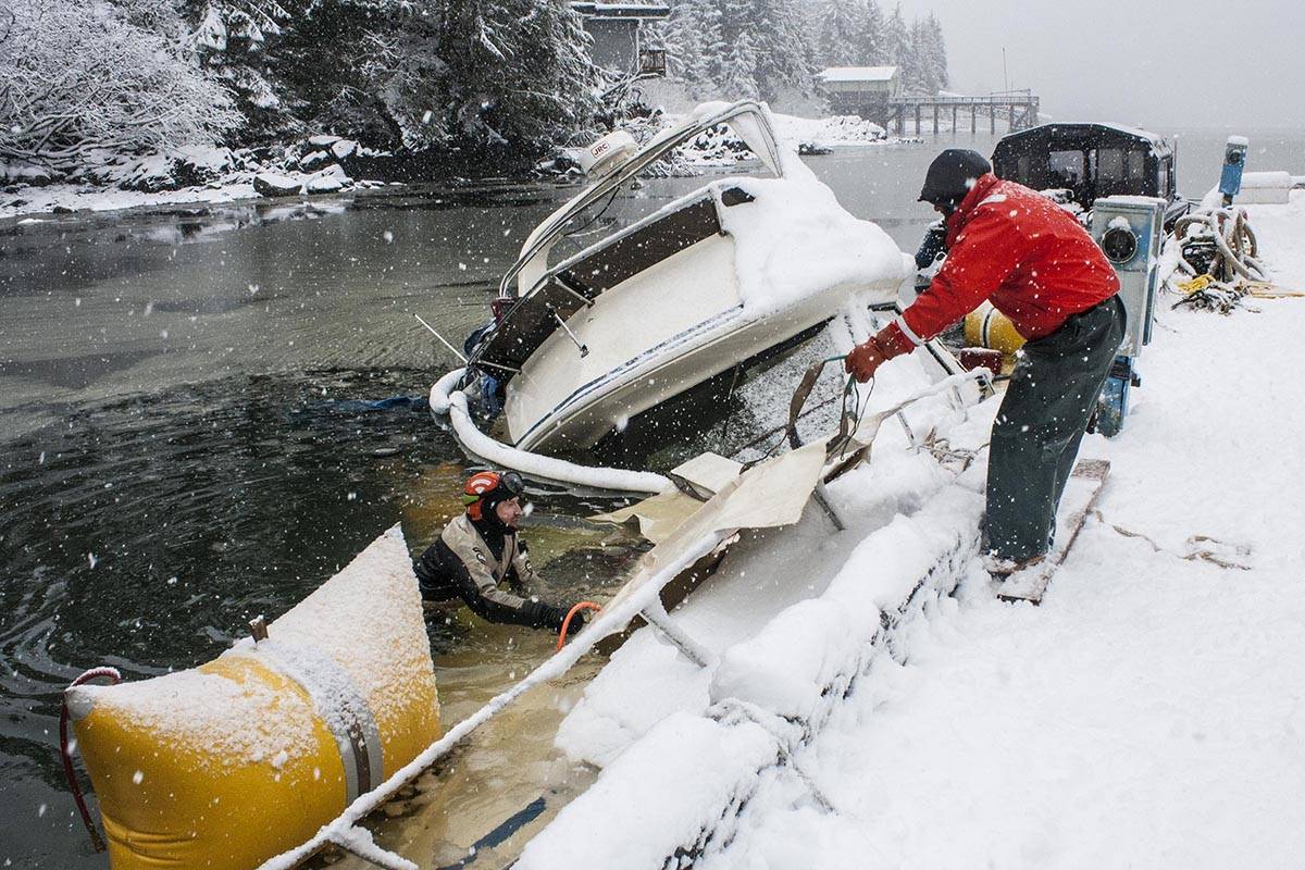 Todd Hadfield, right, Phil Sellick, left, and Alfie Cook, underwater, work to right a capsized vessel at Statter Harbor, Feb. 25, 2020. (Michael S. Lockett | Juneau Empire)