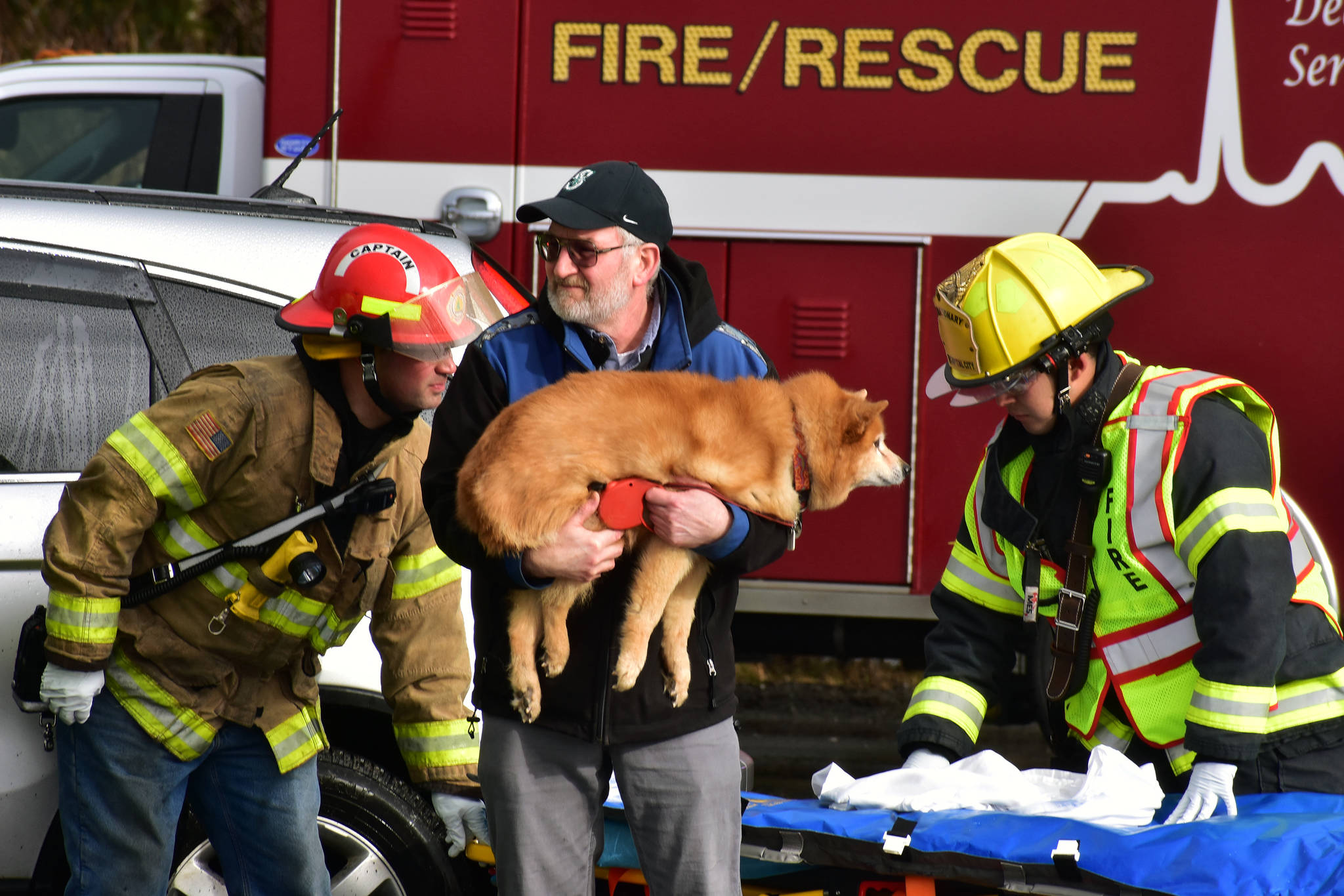 A man holds a dog recovered from a car crash at the intersection of Egan Drive and Glacier Highway on Thursday, Feb. 27, 2020.