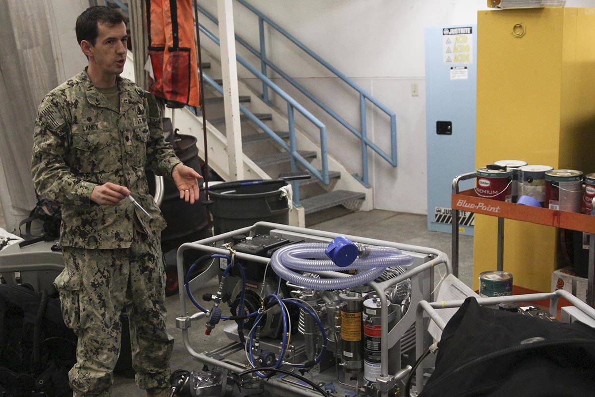 Navy Cmdr. John Laney, commanding officer of Mine Countermeasure Division 31, demonstrates the diver gear the unit uses at Coast Guard Station Juneau, Feb. 29, 2020. (Michael S. Lockett | Juneau Empire)