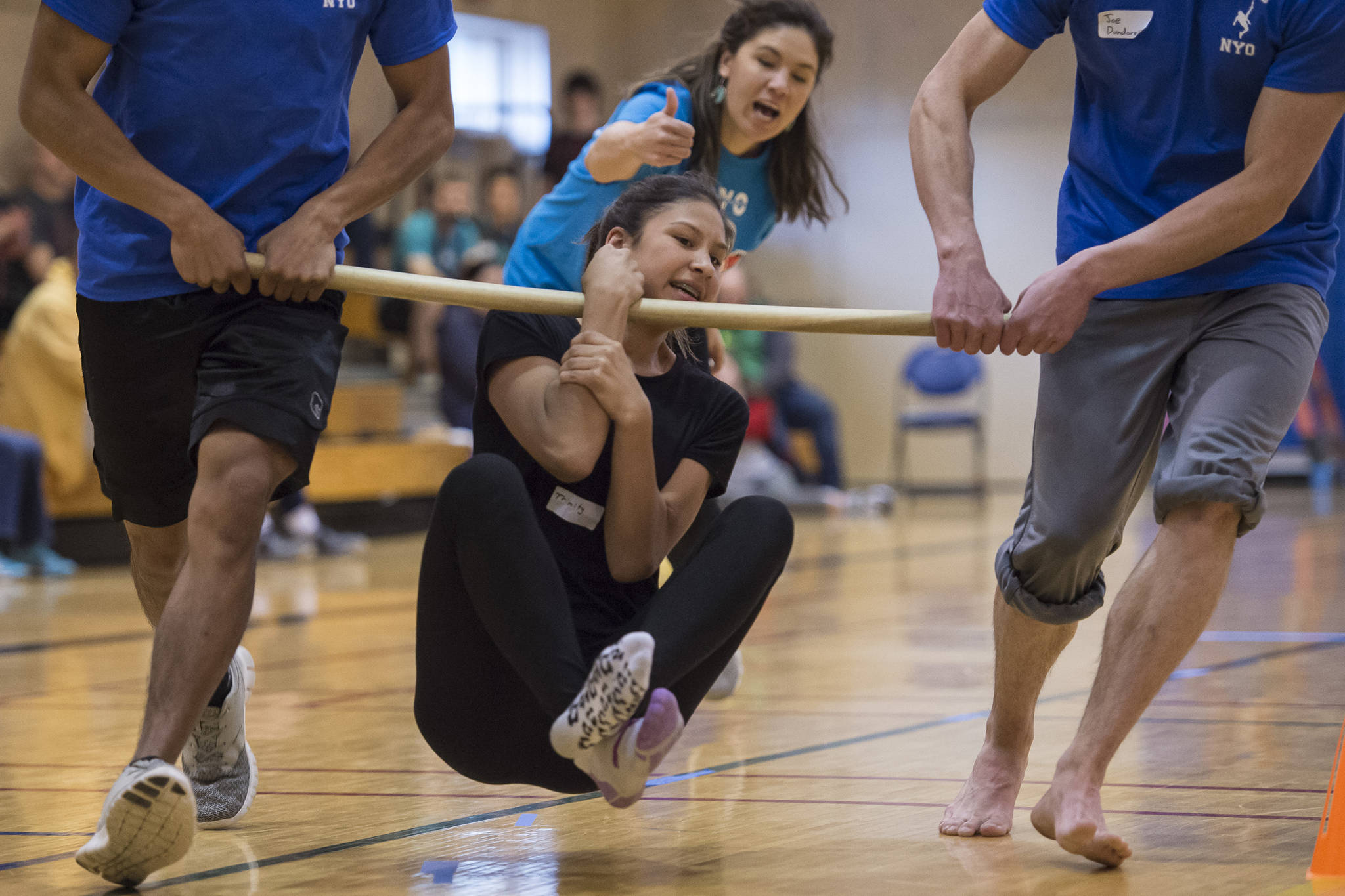 Trinity Jackson, 13, participates in the wrist carry as judge Elizabeth Rexford watches at the Native Youth Olympics 2018 Traditional Games at the University of Alaska Southeast Recreational Center in March 2018. Tuckwood won the event for middle school students. (Michael Penn | Juneau Empire File)