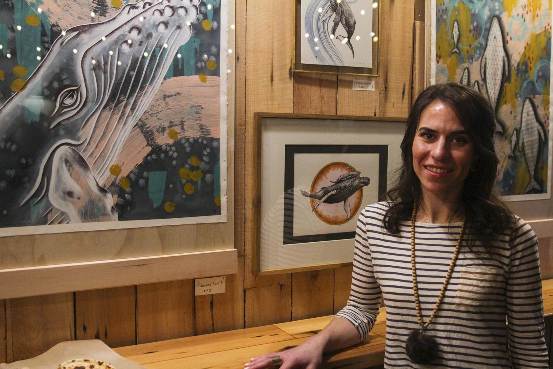 Jacqueline Tingey, a local artist, poses with some of her art at Devil’s Club Brewery during First Friday, March 6, 2020. (Michael S. Lockett | Juneau Empire)