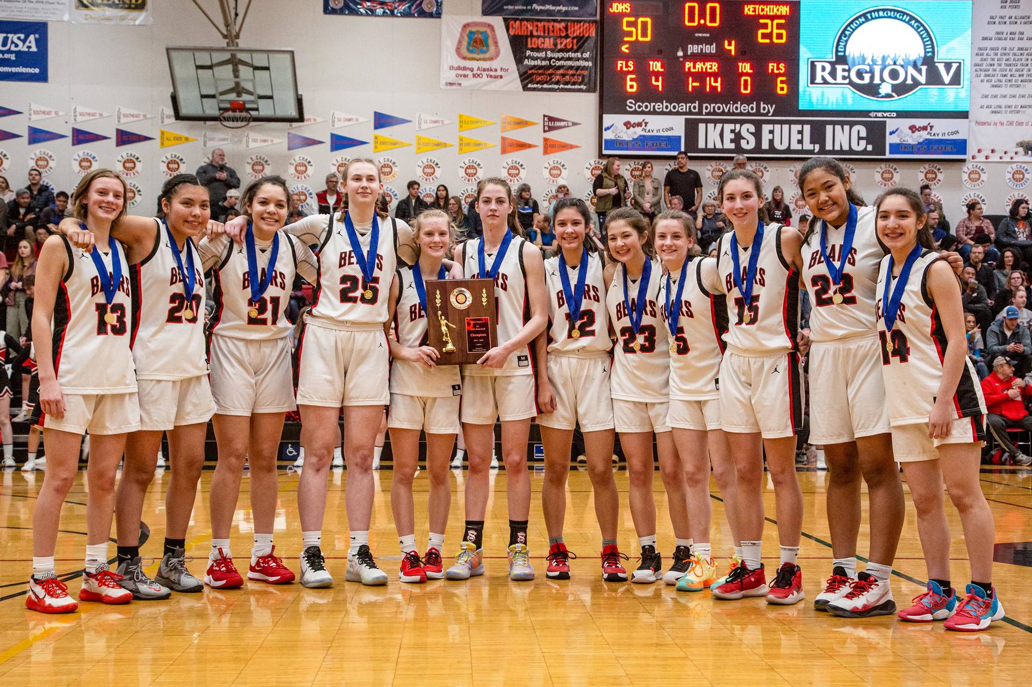 The Juneau-Douglas High School: Yadaa.at Kalé girls basketball team stands with medals and their championship plaque Friday night after winning the Region V 4A championship game.