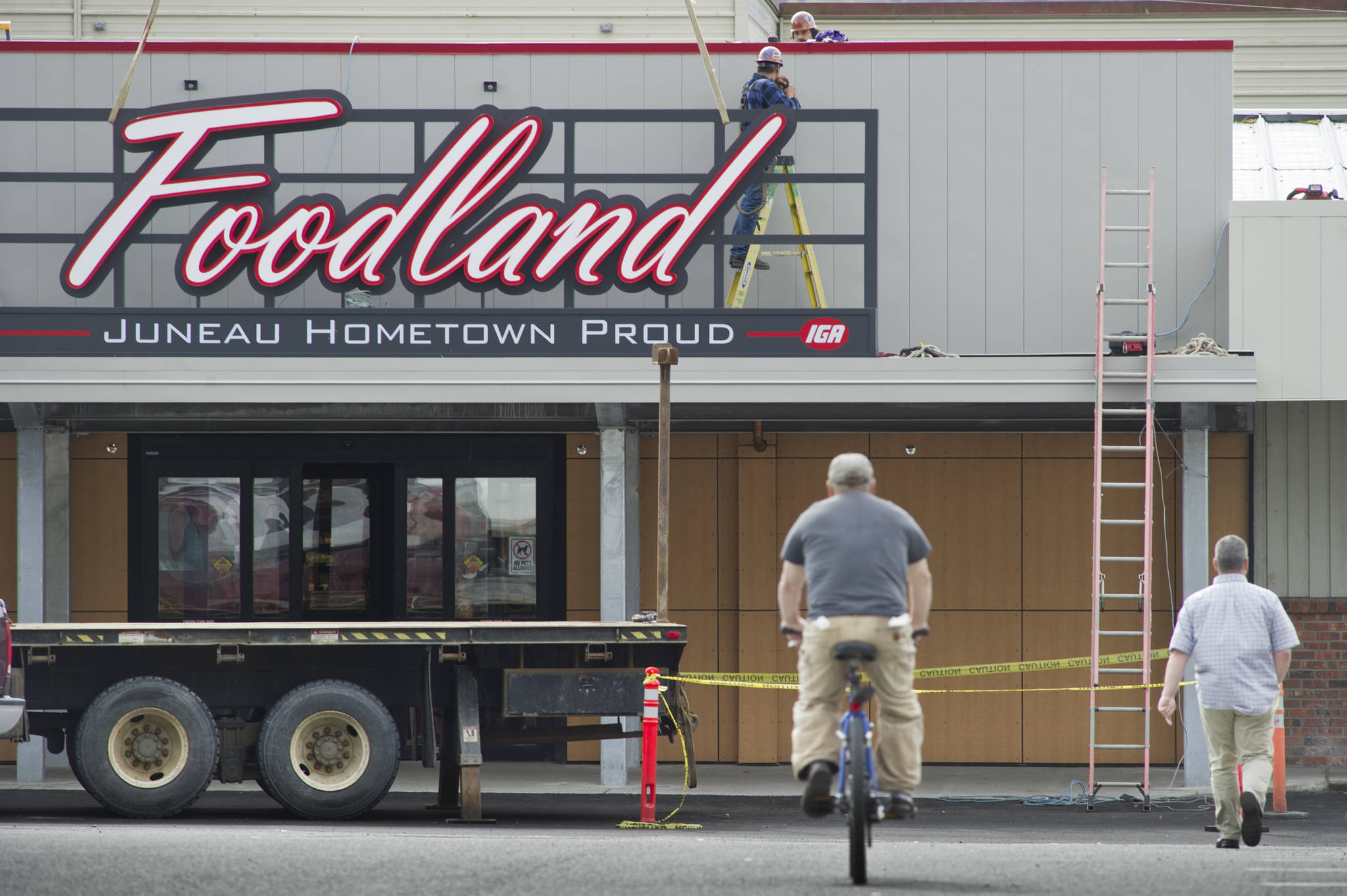 Workmen install a Foodland IGA sign at their downtown store on in August 2016. Foodland and other local grocers are reserving hours for people especially vulnerable to COVID-19. (Michael Penn | Juneau Empire File)