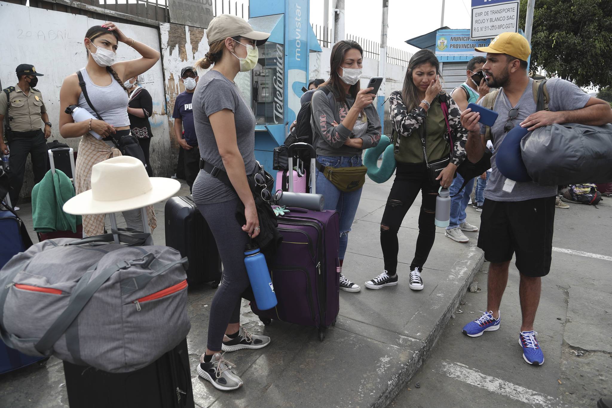 Tourists from the United States wait outside the closed Jorge Chavez International Airport for a member of the U.S. Embassy to escort them to a flight that will fly them back to the U.S., in Callao Peru, Friday, March 20, 2020, on the fifth day of a state of emergency decreed by the government to prevent the spread of the new coronavirus. (AP Photo | Martin Mejia)