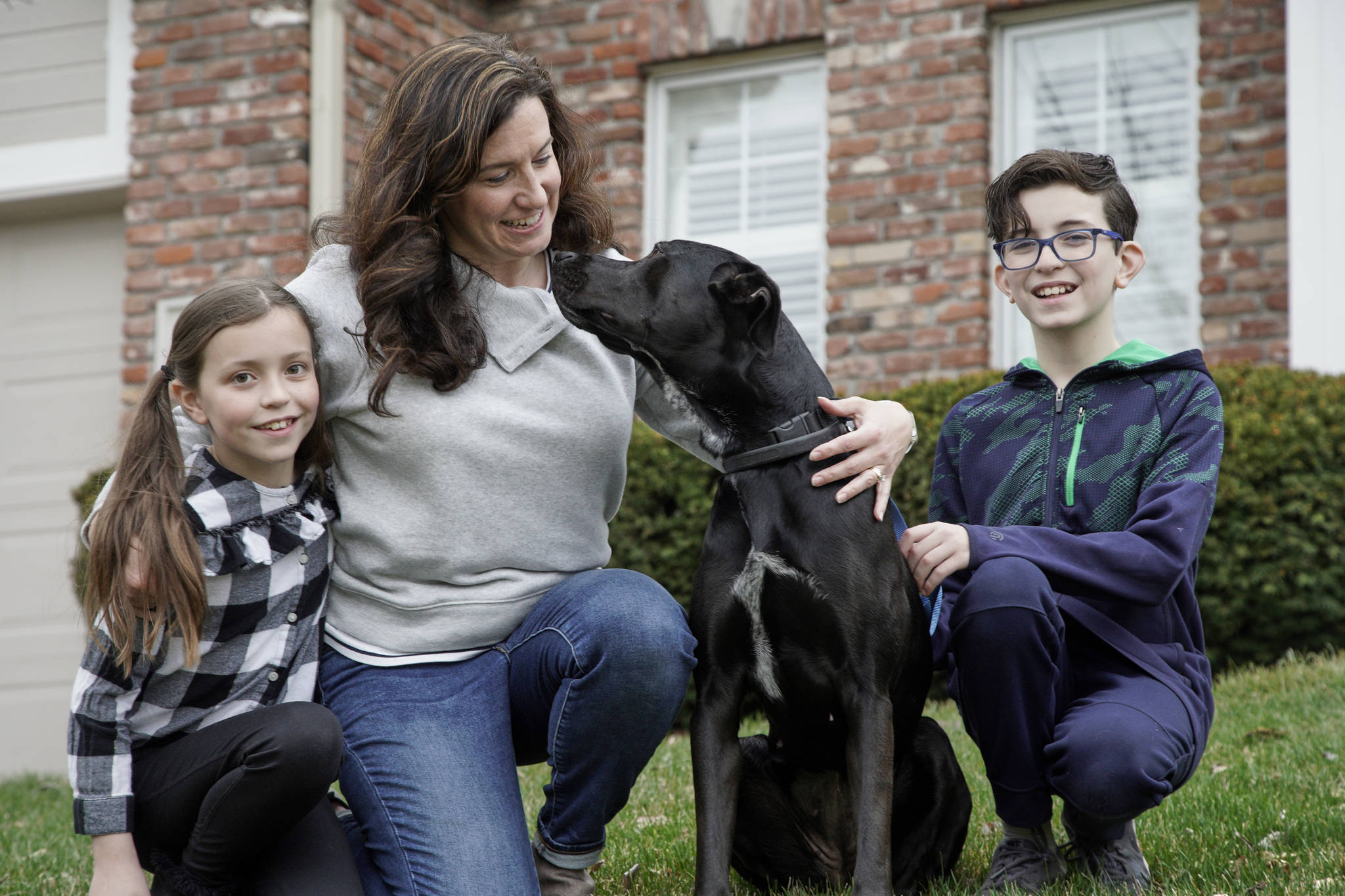 In this March 27, 2020 photo, Kim Simeon and children Annabel, 9, and Brennan, 11, pose for a photo with Nala, a dog they are fostering, in Omaha, Neb. The Simeon family was headed home to Omaha from a much-needed Smoky Mountains vacation when Kim Simeon spotted a social media post from the Nebraska Humane Society, pleading with people to consider fostering a pet. (AP Photo/Nati Harnik)
