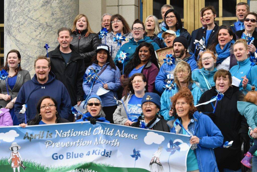 Juneau residents line up with legislators for a picture and a cheer during a Go Blue Day Rally for National Child Abuse Prevention Month at the Capitol on Friday, April 5, 2019. (Michael Penn | Juneau Empire)