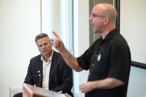 Gov. Mike Dunleavy, background, listens while City and Borough of Juneau Assembly member Wade Bryson speaks in this September 2018 photo. (Michael Penn | Juneau Empire File)