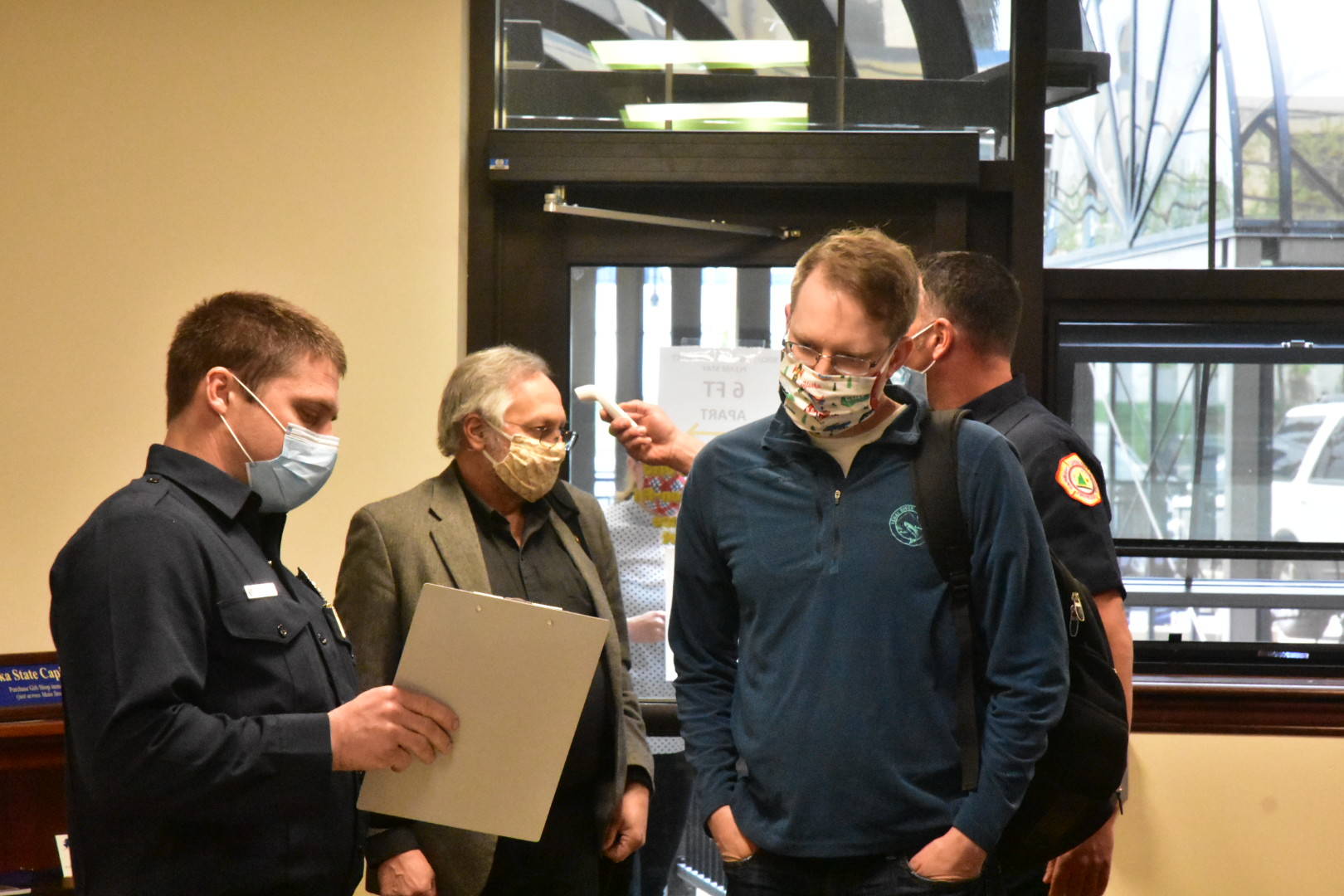 Rep. Lance Pruitt, R-Anchorage, answers screening questions upon entering the Capitol building. Behind him Rep. Dave Talerico, R-Healy, gets his temperature taken on Monday, May 18, 2020. (Peter Segall | Juneau Empire)