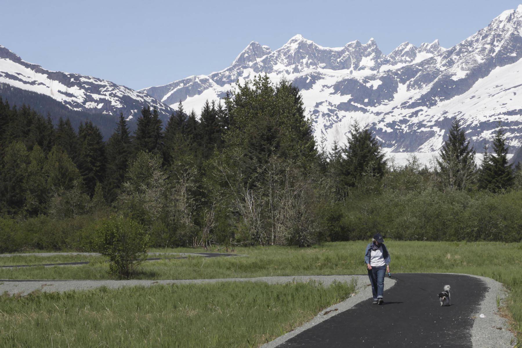 Marie Claire Harris and Roman walk down the newly repaved Kaxdigoowu Héen Dei (Brotherhood Bridge Trail) on, May 27, 2020. The trail has been moved, repaved, and reopened after riverbank erosion threatened the original trail. (Michael S. Lockett | Juneau Empire)