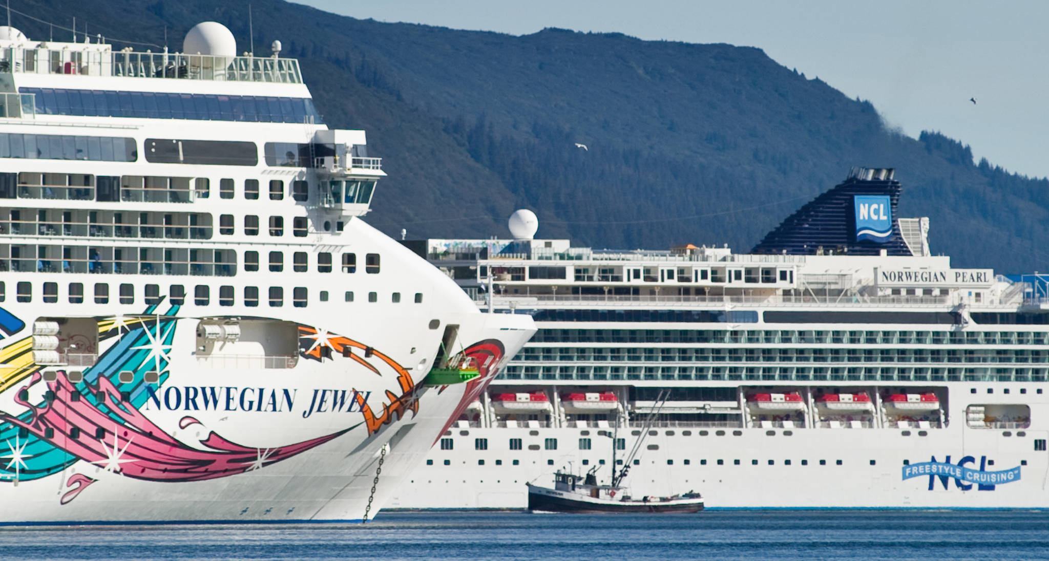 A fishing vessel is drawfed by the Norwegian Cruise Lines’ Norwegian Jewel and Norwegian Pearl in Juneau’s downtown harbor in September 2014. (Michael Penn | Juneau Empire File)