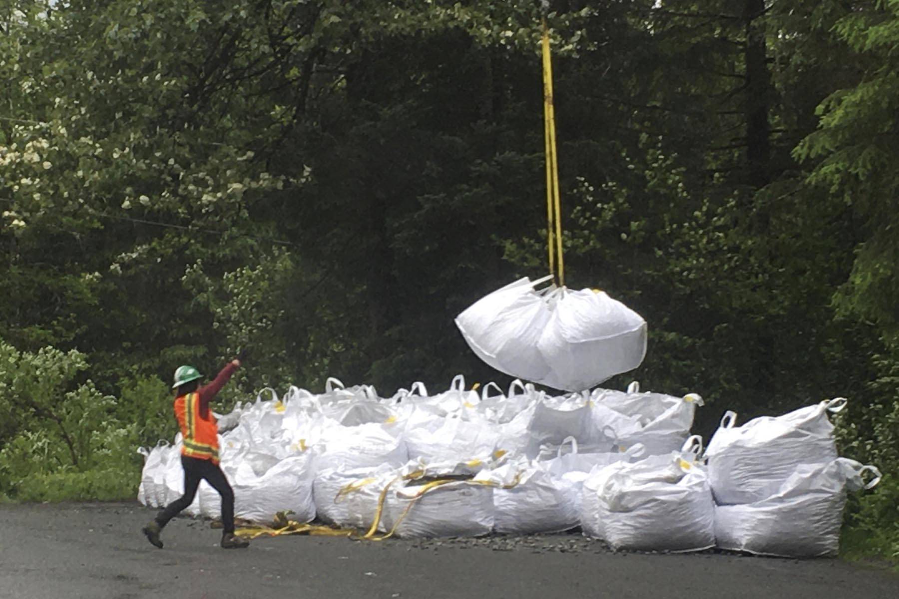 Allison Mickelson, a Trail Mix Inc crew member, guides a multiton load of gravel off a storage area as a K-Max heavy lift helicopter to slingloads it to the construction area on the Horse Tram Trail on Tuesday, June 23, 2020. (Michael S. Lockett | Juneau Empire)