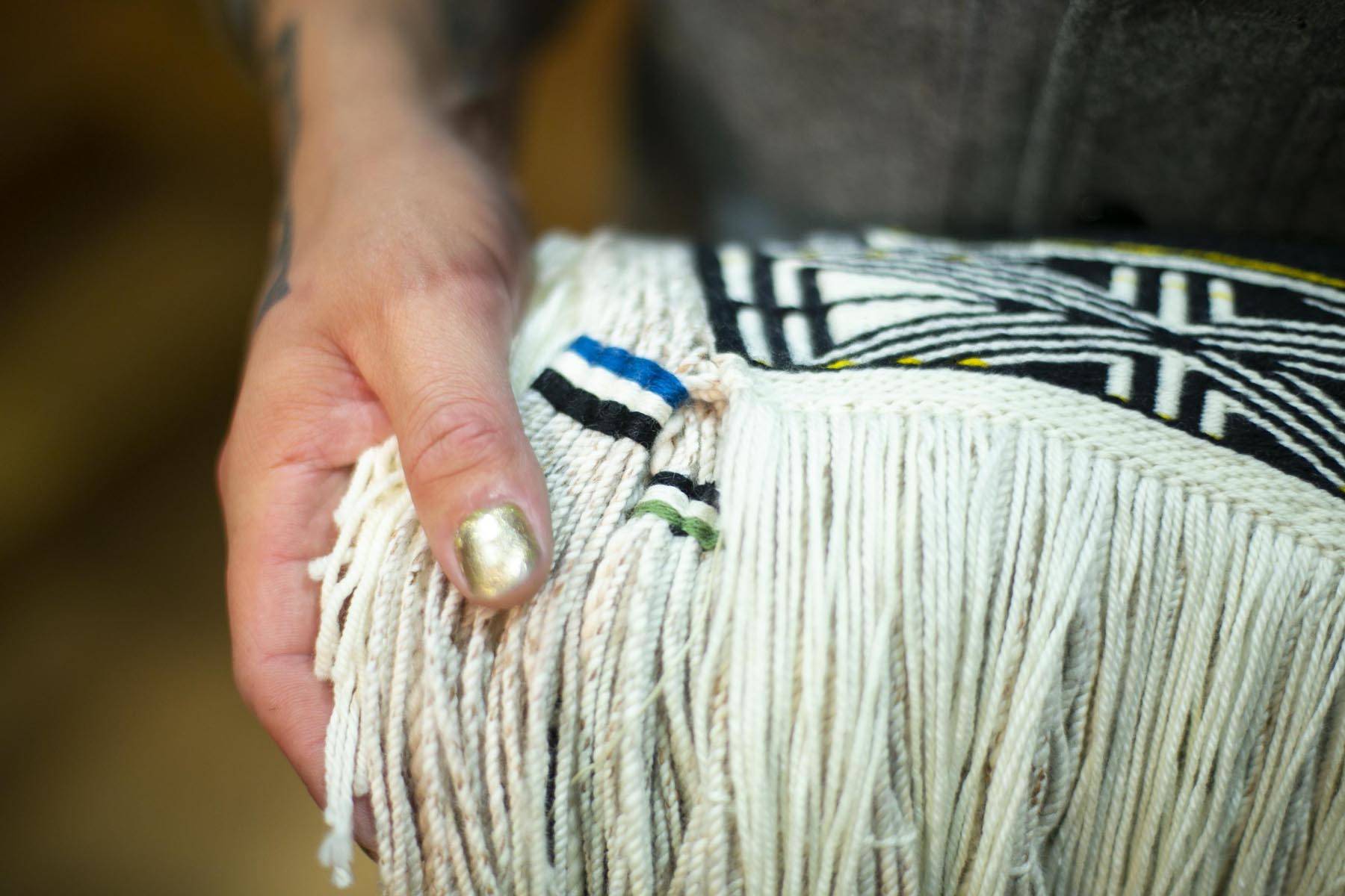 Ricky Tagaban shows the woven artist signatures on the robe he and Lily Hope collaborated to weave at its first dance ceremony at the Sealaska Heritage Institute on Monday, June 22, 2020. (Courtesy photo | Annie Bartholomew)