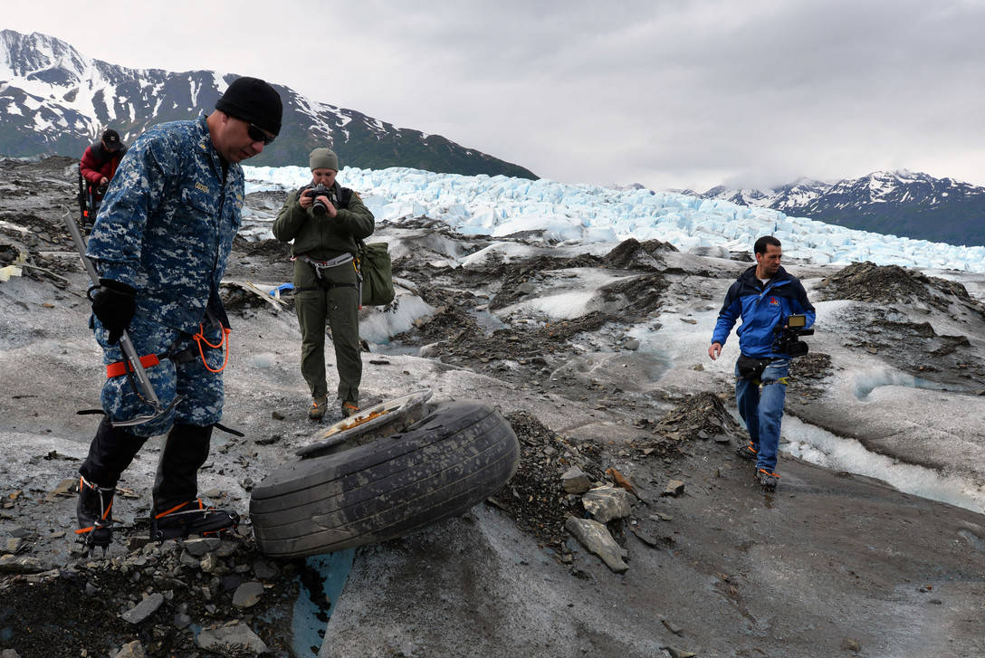 Navy Lt. Commander Paul Cocker (left), Alaskan Command deputy chief of future operations and Operation Colony Glacier project officer, shows local media some of the aircraft debris from the 1952 C-124 Globemaster II aircraft accident June 10. (U.S. Air Force photo | Tech. Sgt. John Gordinier)