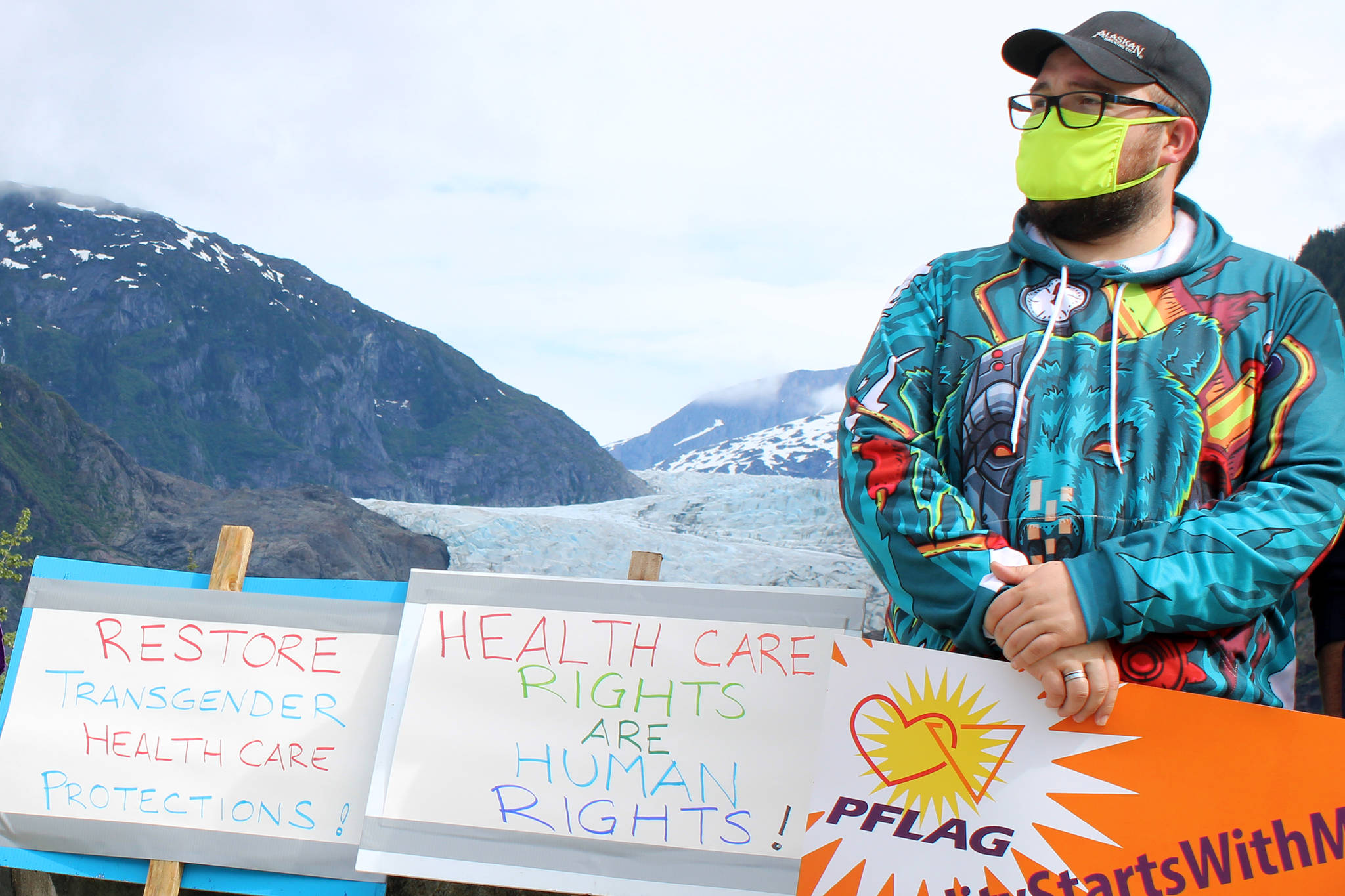 Garrette Reece stands near signs decrying the Trump administration’s decision to reverse an Obama-era rule that provided nondiscrimination protections for LGBTQ+ people when it comes to health care and health insurance. (Ben Hohenstatt | Juneau Empire)