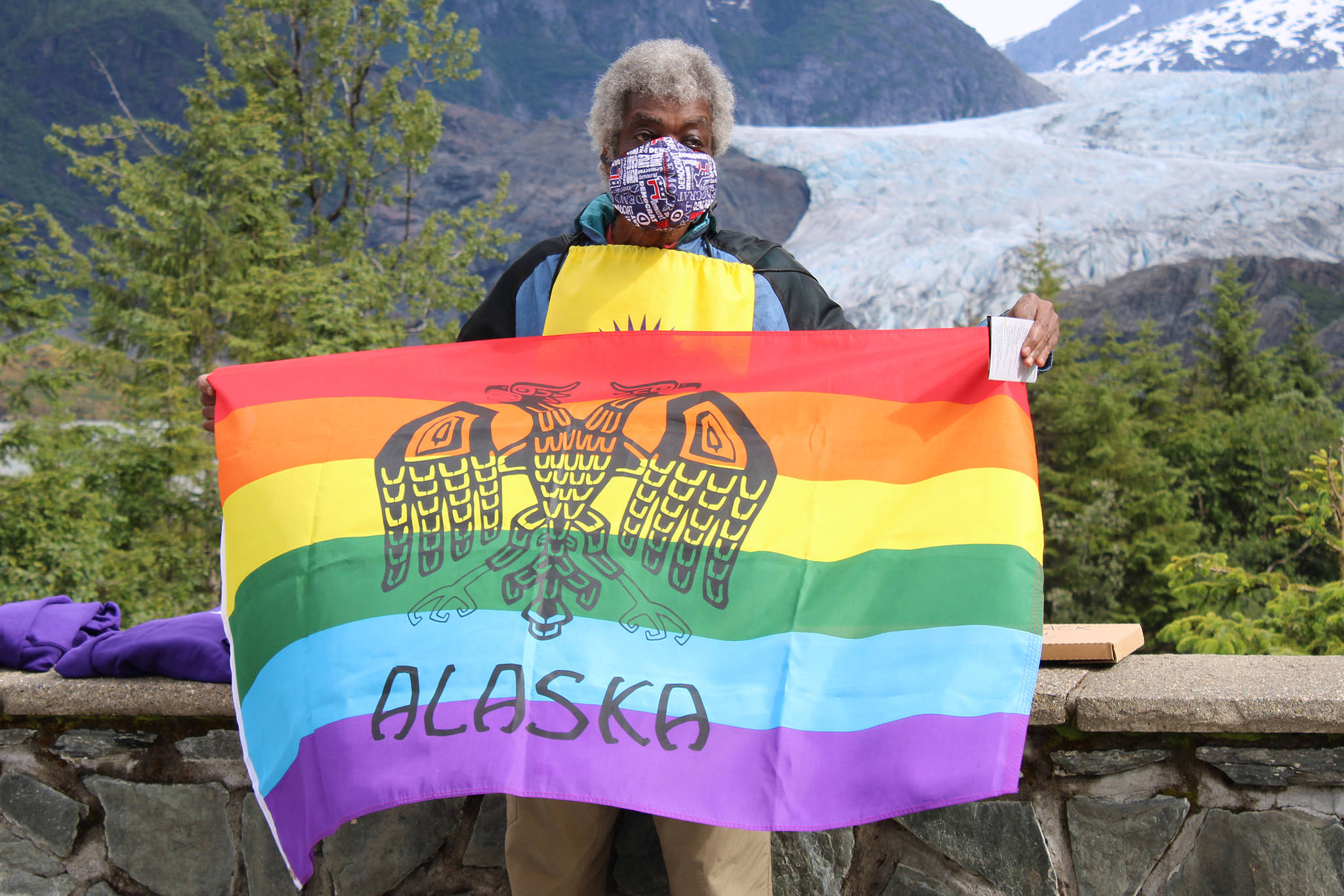 Willie Anderson holds up a flag in front at a short PFLAG gathering held near the Mendenhall Glacier Visitor Center. (Ben Hohenstatt | Juneau Empire)