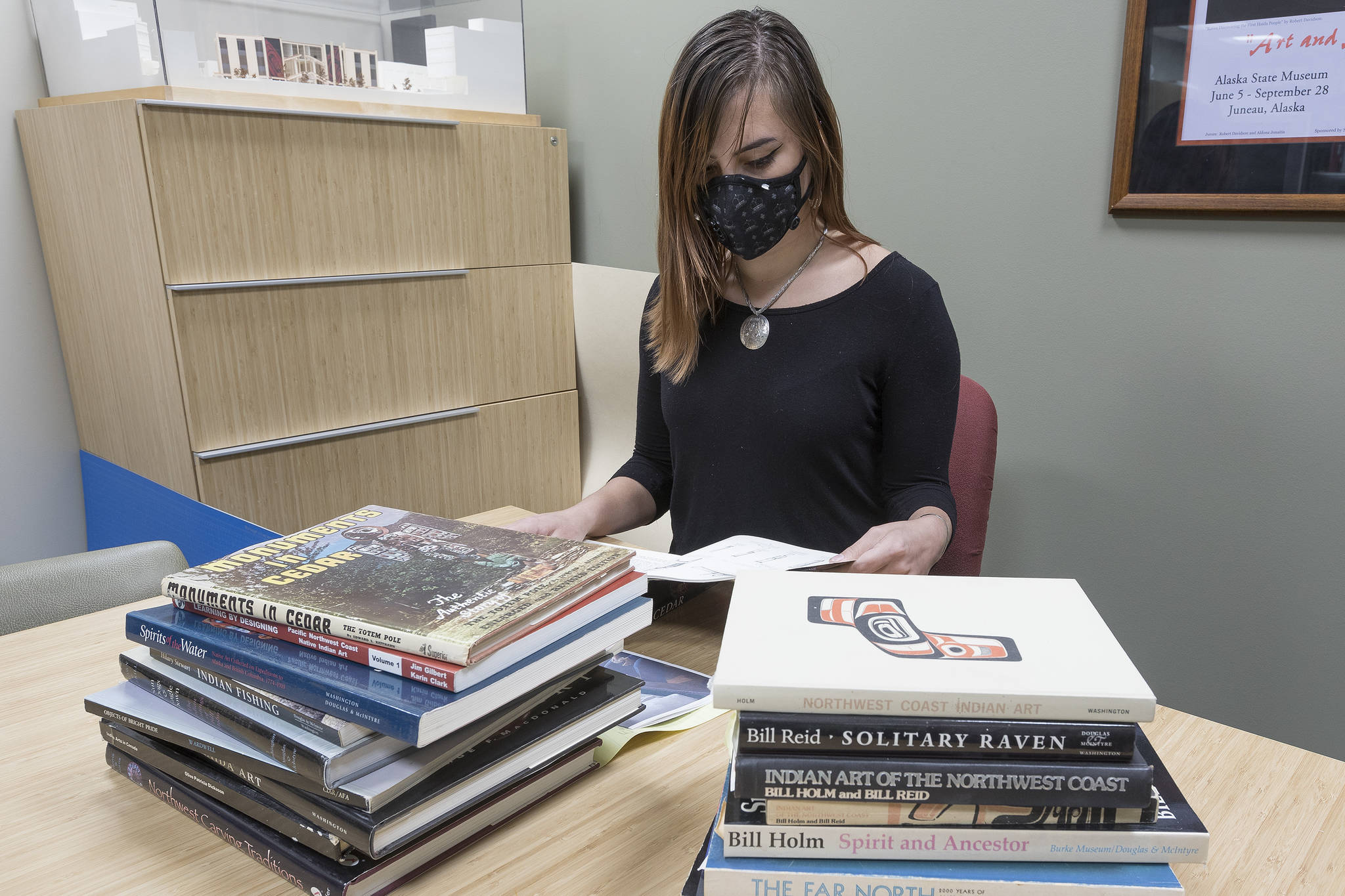 Sealaska Heritage Institute media intern and Northwest Coast art student Mikayla Mitchell peruses some of the books recently donated to the institute by Lesley Jacobs. (Courtesy Photo | Brian Wallace for Sealaska Heritage Institute)