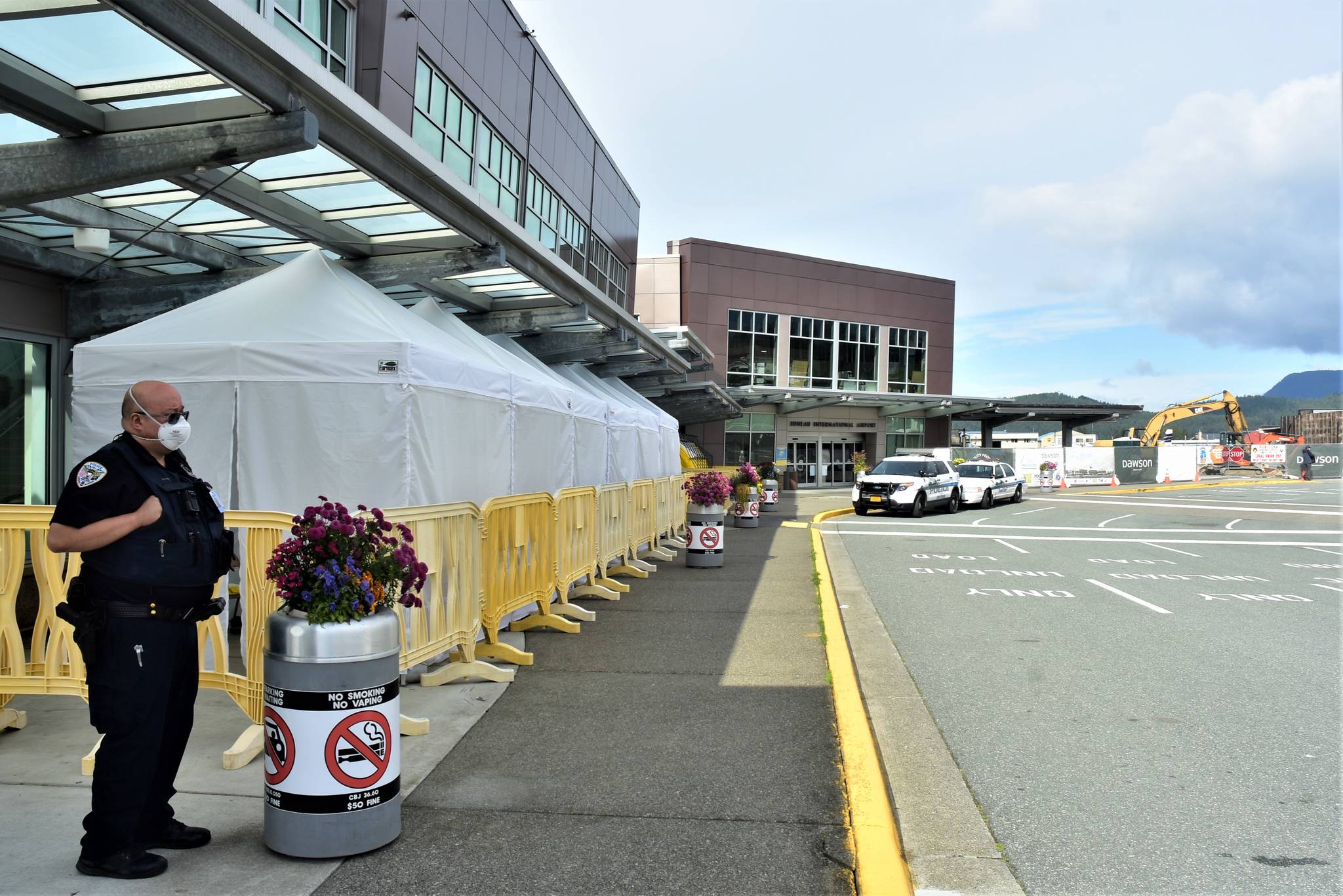 A Juneau Police Department officer at the Juneau International Airport on Tuesday, July 28, 2020. Nonresident out-of-state arrivals will have to provide negative COVID-19-test results under a revised travel mandate from Gov. Mike Dunleavy. (Peter Segall / Juneau Empire)
