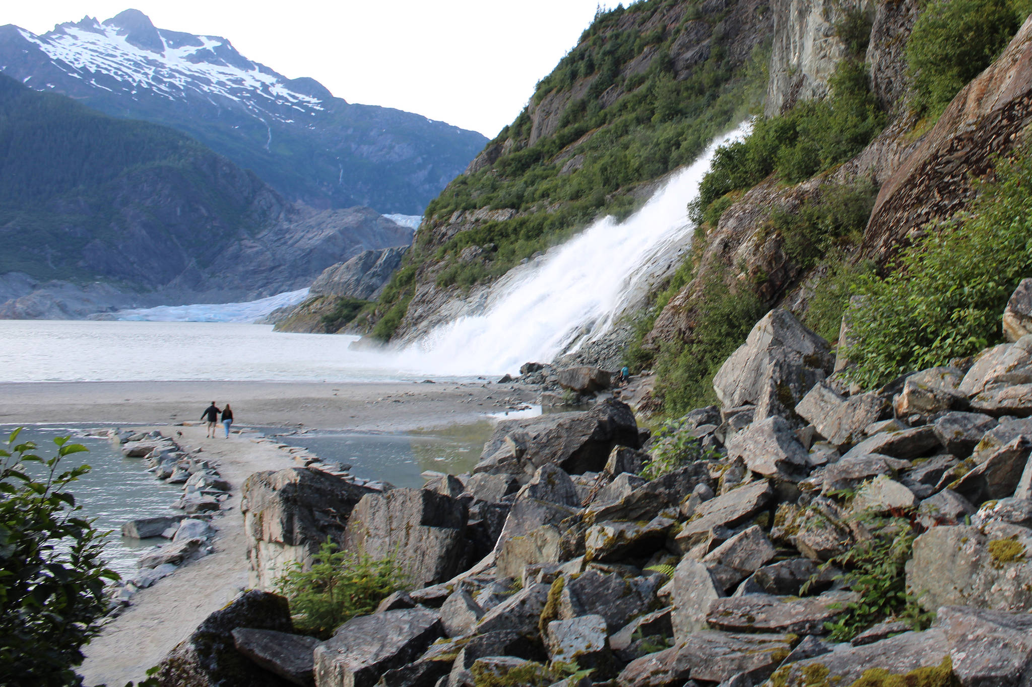 People walk near Nugget Falls Thursday, July 30, 2020. A flood warning is in effect for Mendenhall Lake and Mendenhall River through 10 a.m. Saturday, Aug. 1, 2020. As water levels rise, recreation sites near the glacier may be hazardous or inaccessible. (Ben Hohenstatt / Juneau Empire)