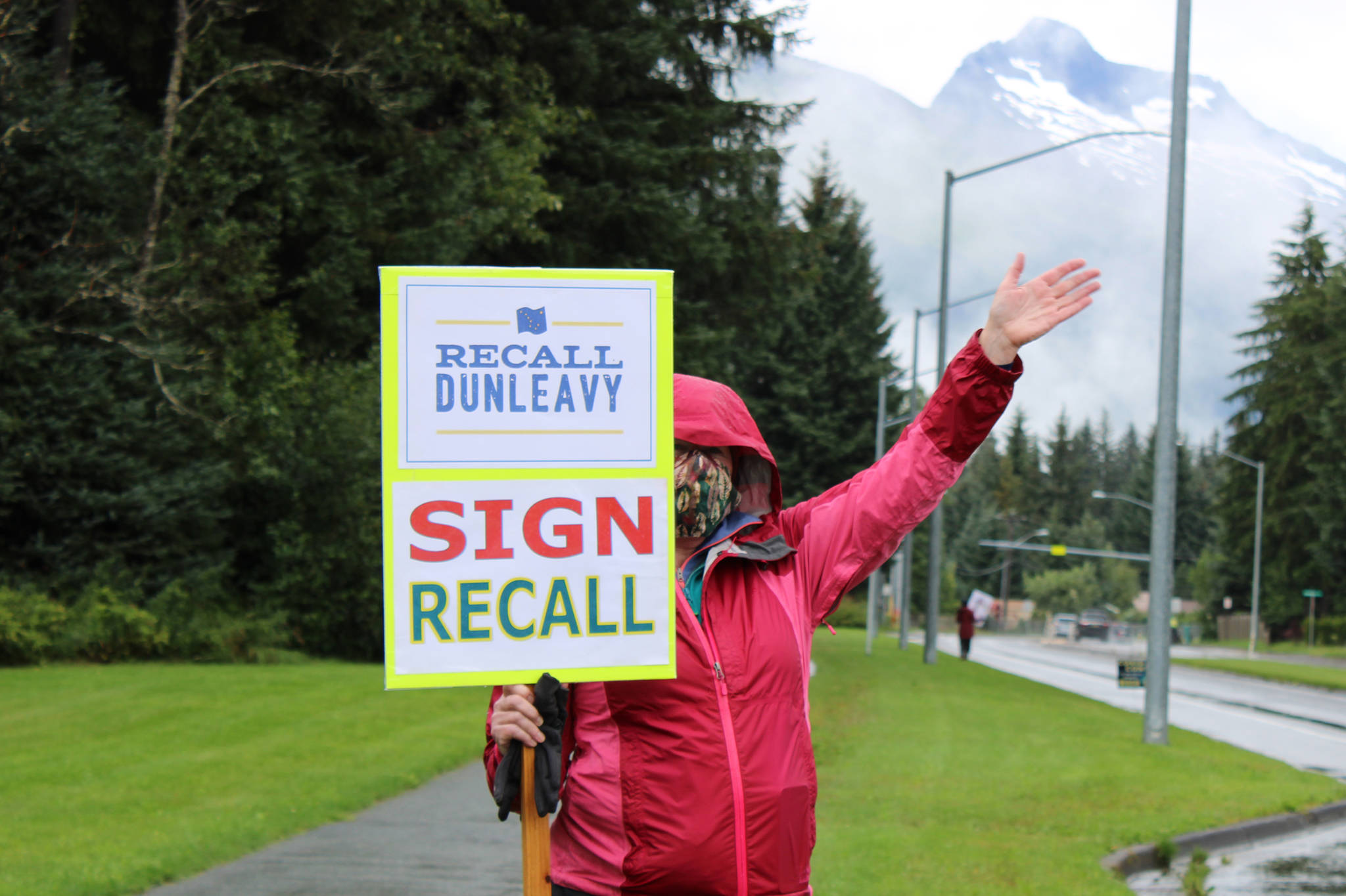 Ben Hohenstatt / Juneau empire                                 A volunteer, who declined to be identified, signals to passersby outside the Mendenhall Valley Public Library during a Recall Dunleavy event Saturday, Aug. 15, 2020.