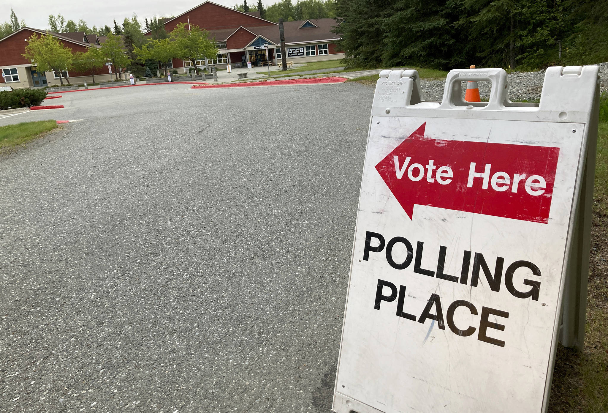 A Vote Here sign stands in the driveway outside Benny Benson Elementary School in Anchorage, Alaska, on Tuesday, Aug. 18, 2020. The Alaska Primary election is held Tuesday, when key races included the U.S. Senate, U.S. House and legislative races. (AP Photo/Mark Thiessen)
