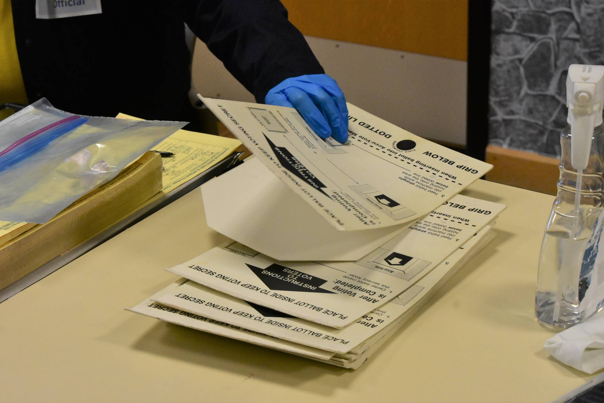 Poll workers at the Douglas Community Building show the coverings used to keep completed ballots covered and secret which this year are also being used to reduce contact with the ballot itself. The laminated coverings are sanitized after each use, part of the extra health precautions in place for the 2020 Primary Election on Tuesday, Aug. 18, 2020. (Peter Segall / Juneau Empire)