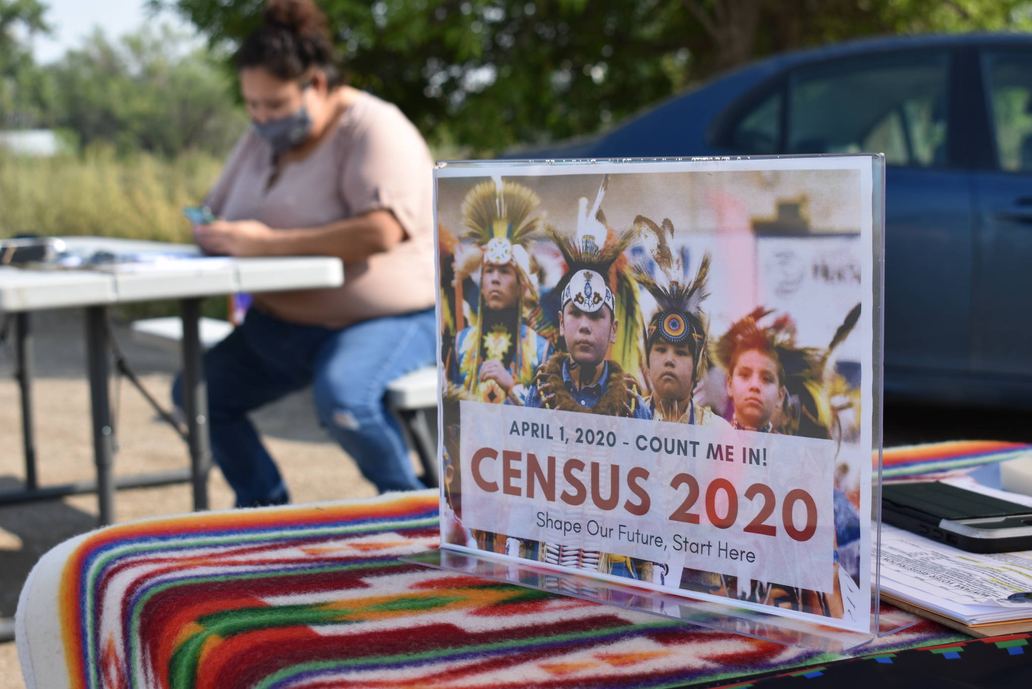 A sign promoting Native American participation in the U.S. census is displayed as Selena Rides Horse enters information into her phone on behalf of a member of the Crow Indian Tribe in Lodge Grass, Mont. on Wednesday, Aug. 26, 2020. There are more than 300 Native American reservations across the country, and almost all lag the rest of the country in participation in the census. (AP Photo / Matthew Brown)