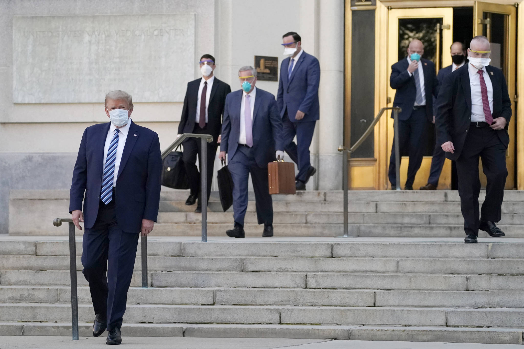AP Photo / Evan Vucci President Donald Trump (left) walks out of Walter Reed National Military Medical Center on Monday to return to the White House after receiving treatments for covid-19 at the Walter Reed Medical Center in Bethesda, Maryland.