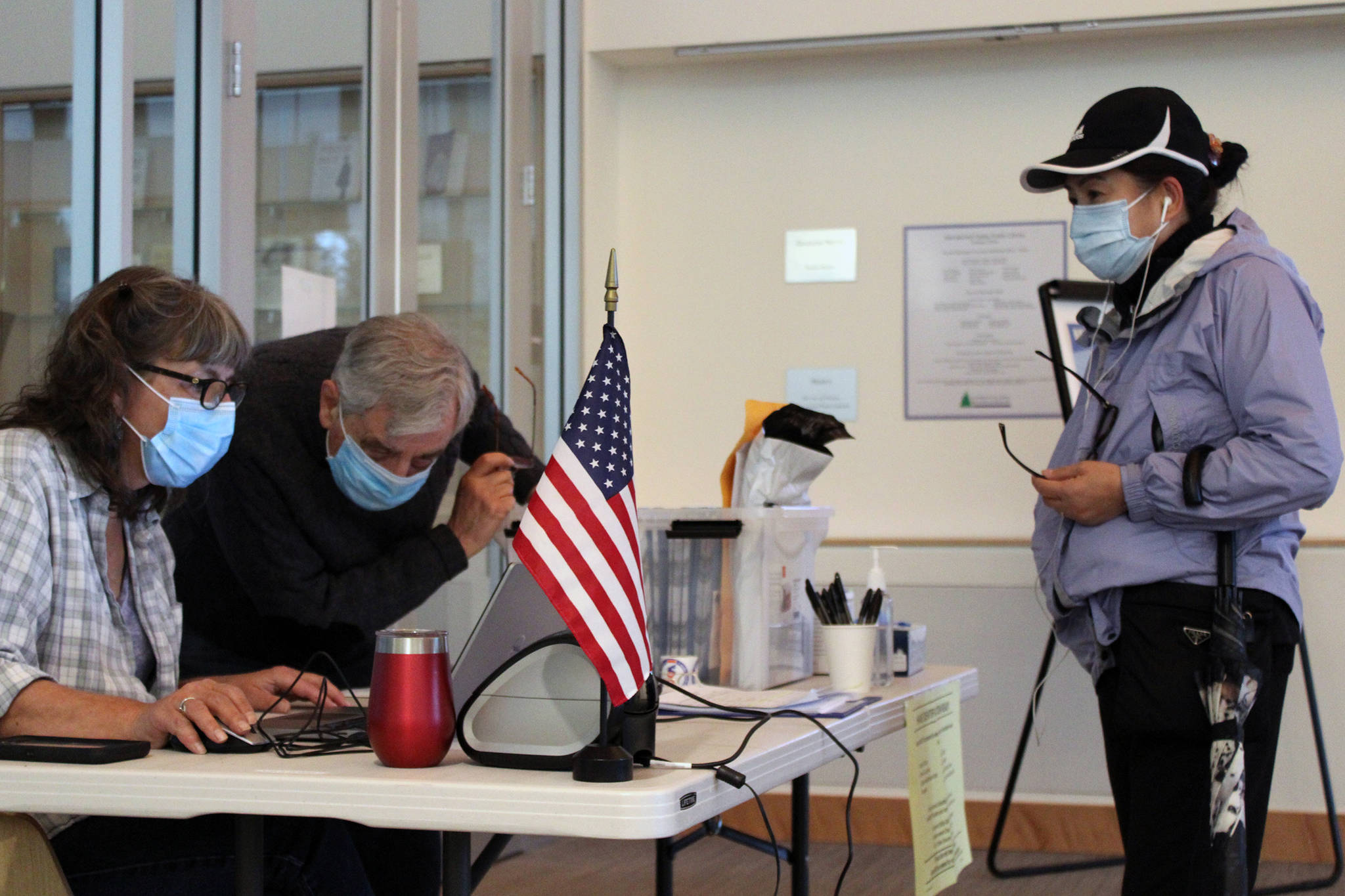 Ben Hohenstatt / Juneau Empire Election officials Kim Peterson and Jack Chenoweth look up voter information for Mary Ellen Yadao on Oct. 6, 2020.