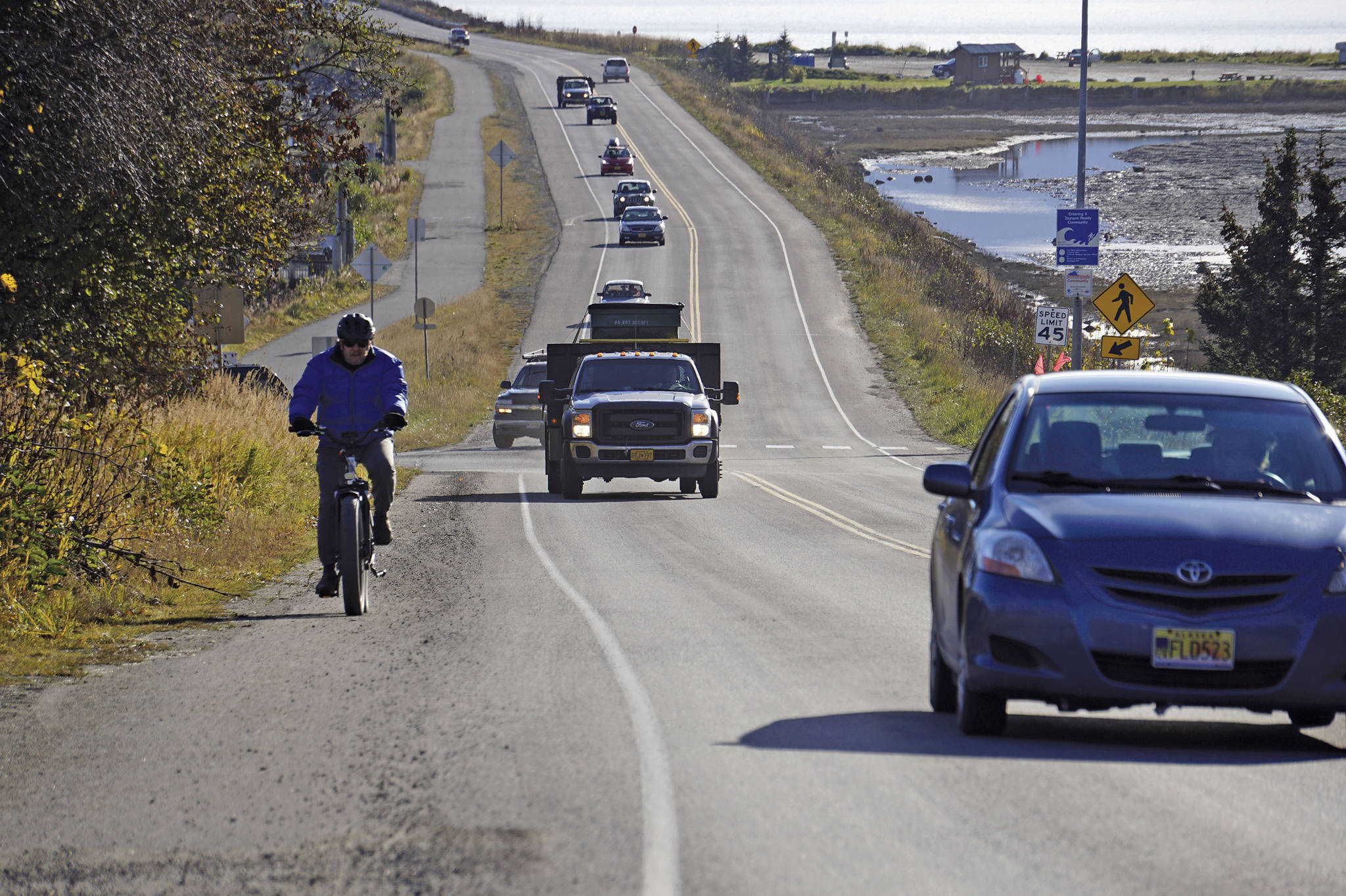 A biker leads a line of cars driving off the Homer Spit at about on Monday, Oct. 19, 2020, in Homer, Alaska after a tsunami evacuation order was issued for low-lying areas in Homer. (Michael Armstrong / Homer News via AP)
