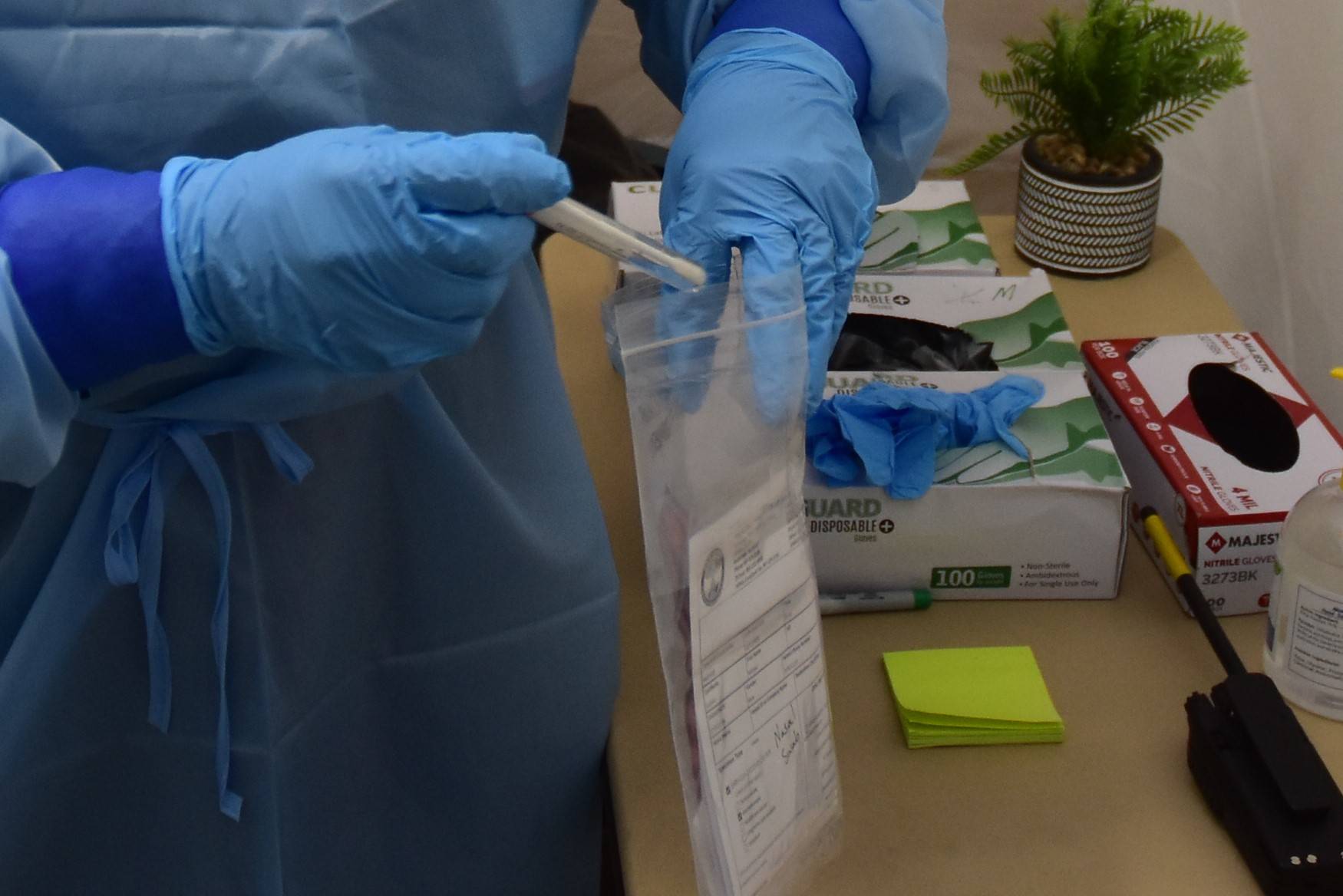 Emergency worker Melanie Chavez takes a COVID-19 test sample at the Juneau International Airport screening site on Monday, Oct. 12, 2020. City officials said Tuesday contact tracers are behind in tracking down positive COVID-19 cases. (Peter Segall / Juneau Empire)