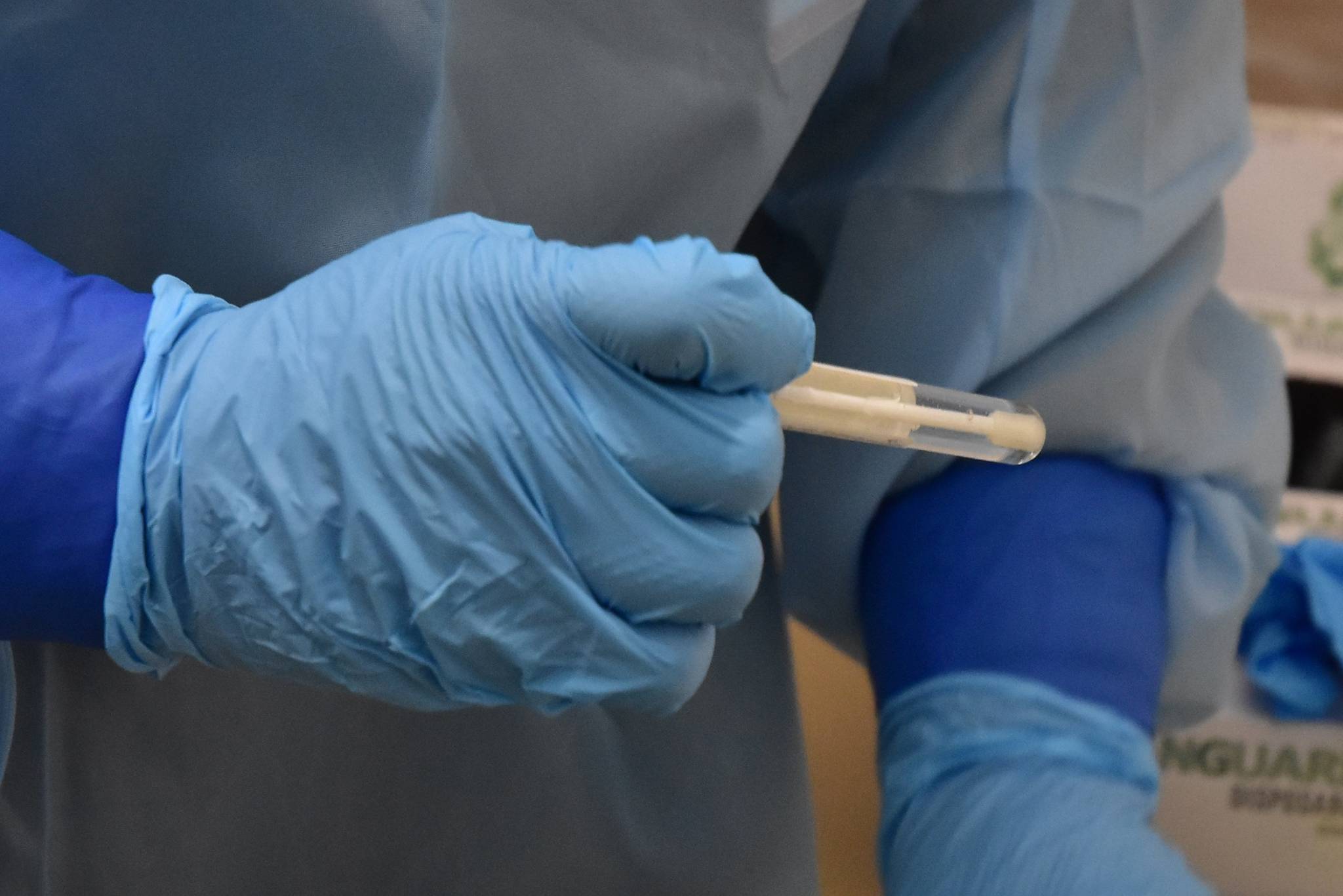 Emergency worker Melanie Chavez takes a COVID-19 test sample at the Juneau International Airport screening site on Monday, Oct. 12, 2020. Bartlett Regional Hospital staff are hoping to have a testing machine operational early next year that will allow the city to process its own COVID-19 samples. (Peter Segall / Juneau Empire)