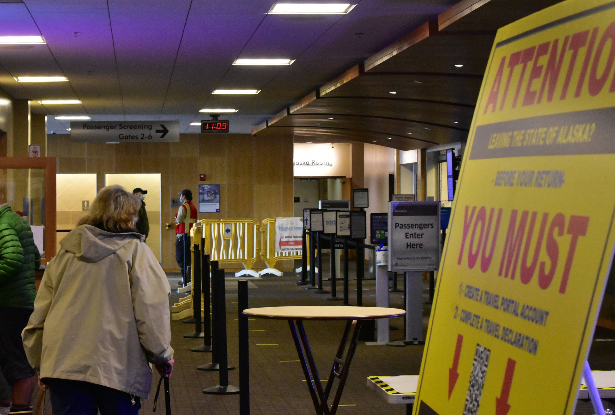 Passengers at the Juneau International Airport make their way past signage notifying the public about the state’s travel restrictions on Monday, Nov. 15, 2020. Gov. Mike Dunleavy issued a new emergency declaration which took effect Monday, which outlined a number of travel guidelines for both in-state and out-of-state travel. (Peter Segall / Juneau Empire)