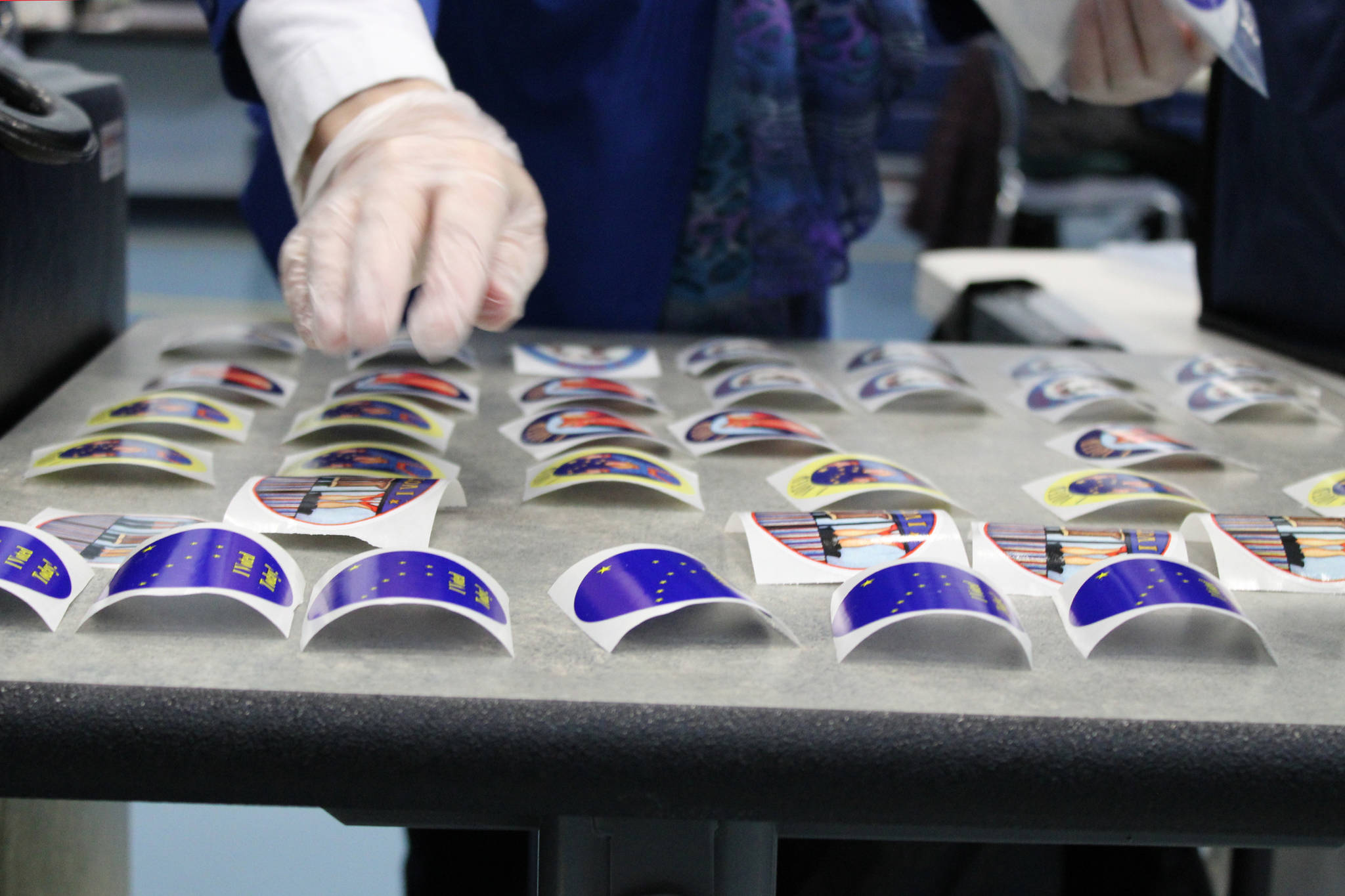 An election official lays out “I voted” stickers on Tuesday, Nov. 3. Stickers for the 2020 general election featured designs by Alaskan artist Barbara Lavallee. (Ben Hohenstatt / Juneau Empire)
