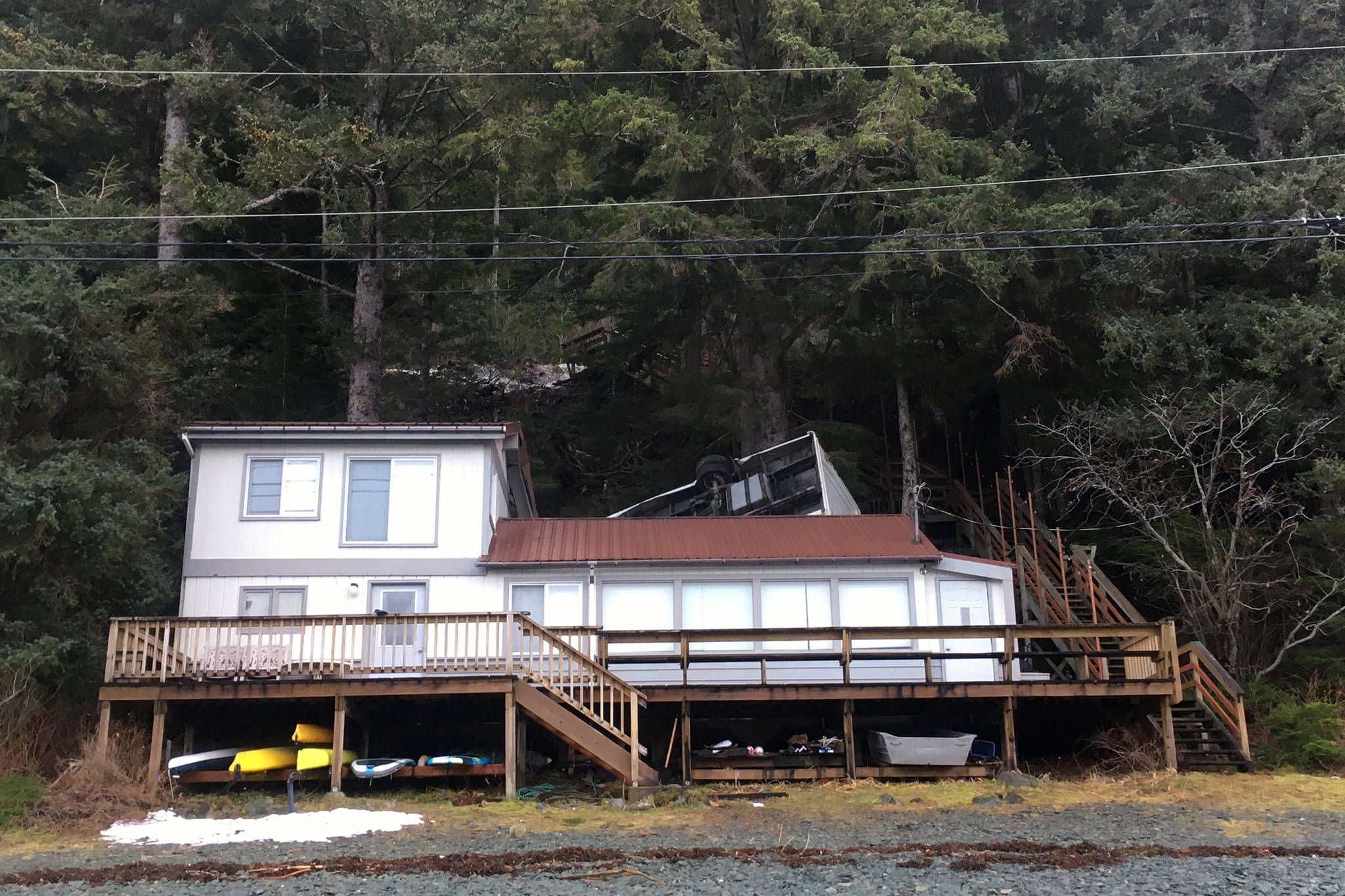 A bus landed on the roof of a house out the road after driving off the road on Nov. 26, 2020. The bus and house were empty, and the driver of the bus was uninjured. (Michael S. Lockett / Juneau Empire)