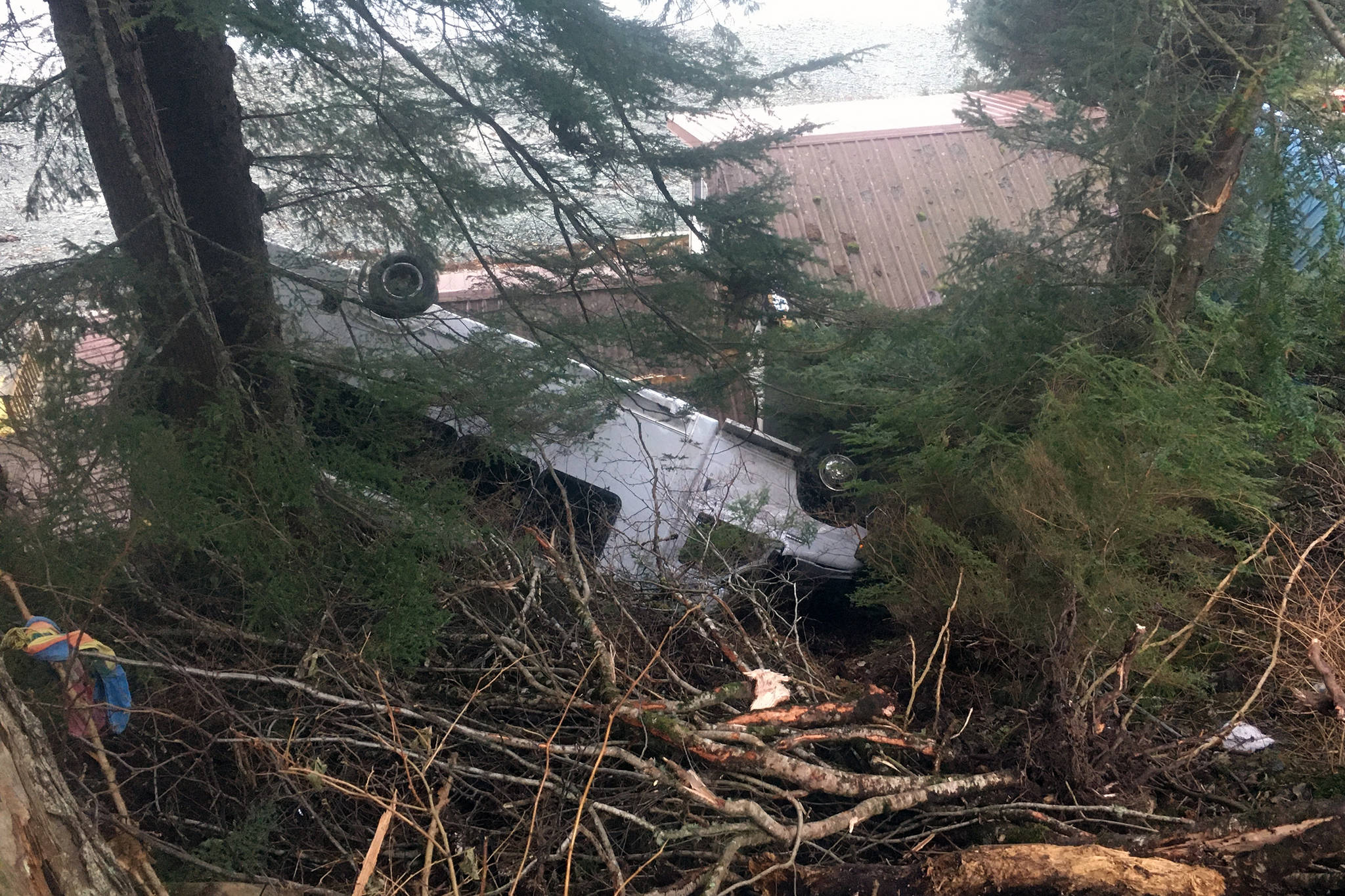 A bus landed on the roof of a house out the road after driving off the road on Nov. 26, 2020. The bus and house were empty, and the driver of the bus was uninjured. (Michael S. Lockett / Juneau Empire)