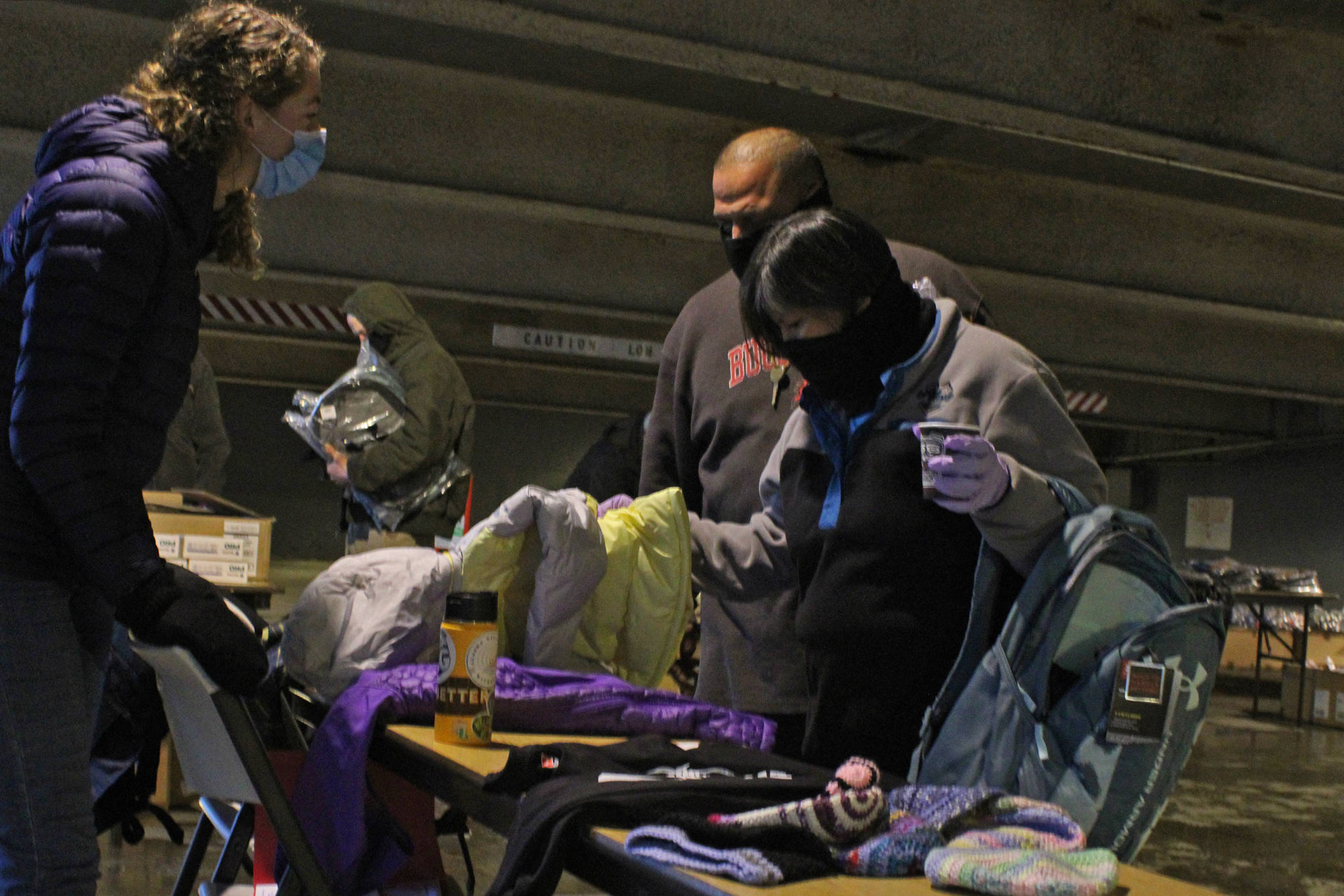 Kaitlyn Conway, youth outreach coordinator with the Zach Gordon Youth Center, talks to people who identified themselves as Vivian and Al, Saturday in the Marine Parking Garage. About 60 people had turned out to the event to provide on-the-spot assistance to people experiencing homelessness within its first hour, according to organizers. (Ben Hohenstatt / Juneau Empire)