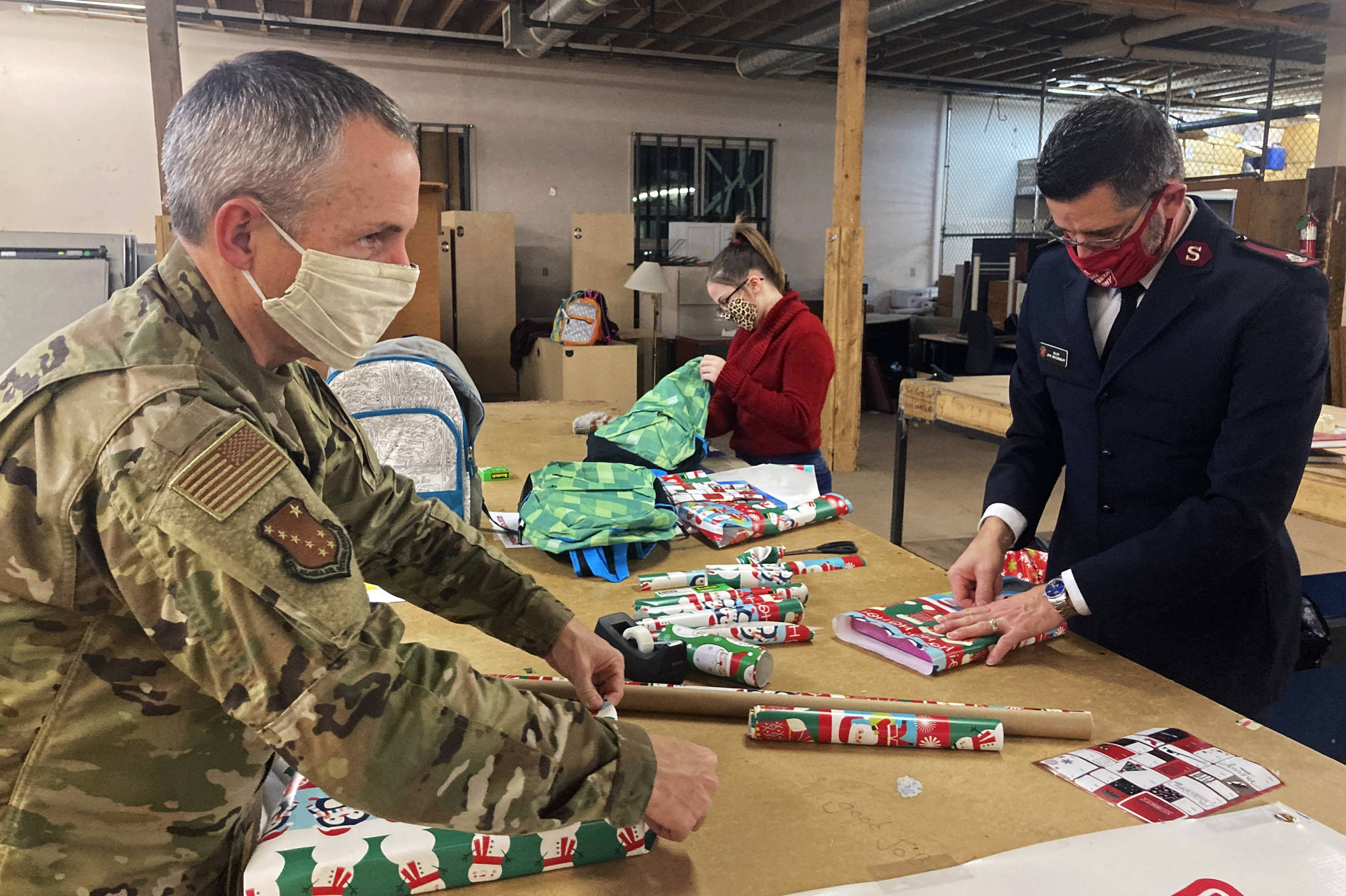 Chief Master Sgt. Winfield Hinkley Jr., Command Senior Enlisted Leader of the Alaska National Guard, left, Makayla Hikley, middle, and Maj. John Brackenbury, divisional commander with the Salvation Army, Alaska Division, wrap gifts in Anchorage, Alaska, that will be sent to children in three rural Alaska villages, on Nov. 17, 2020. The Alaska National Guard and the Salvation Army were able to provide and deliver gifts for the programs 65th year, but had to scale back distribution parties that are normally held in the villages because of COVID-19. (AP Photo / Mark Thiessen)