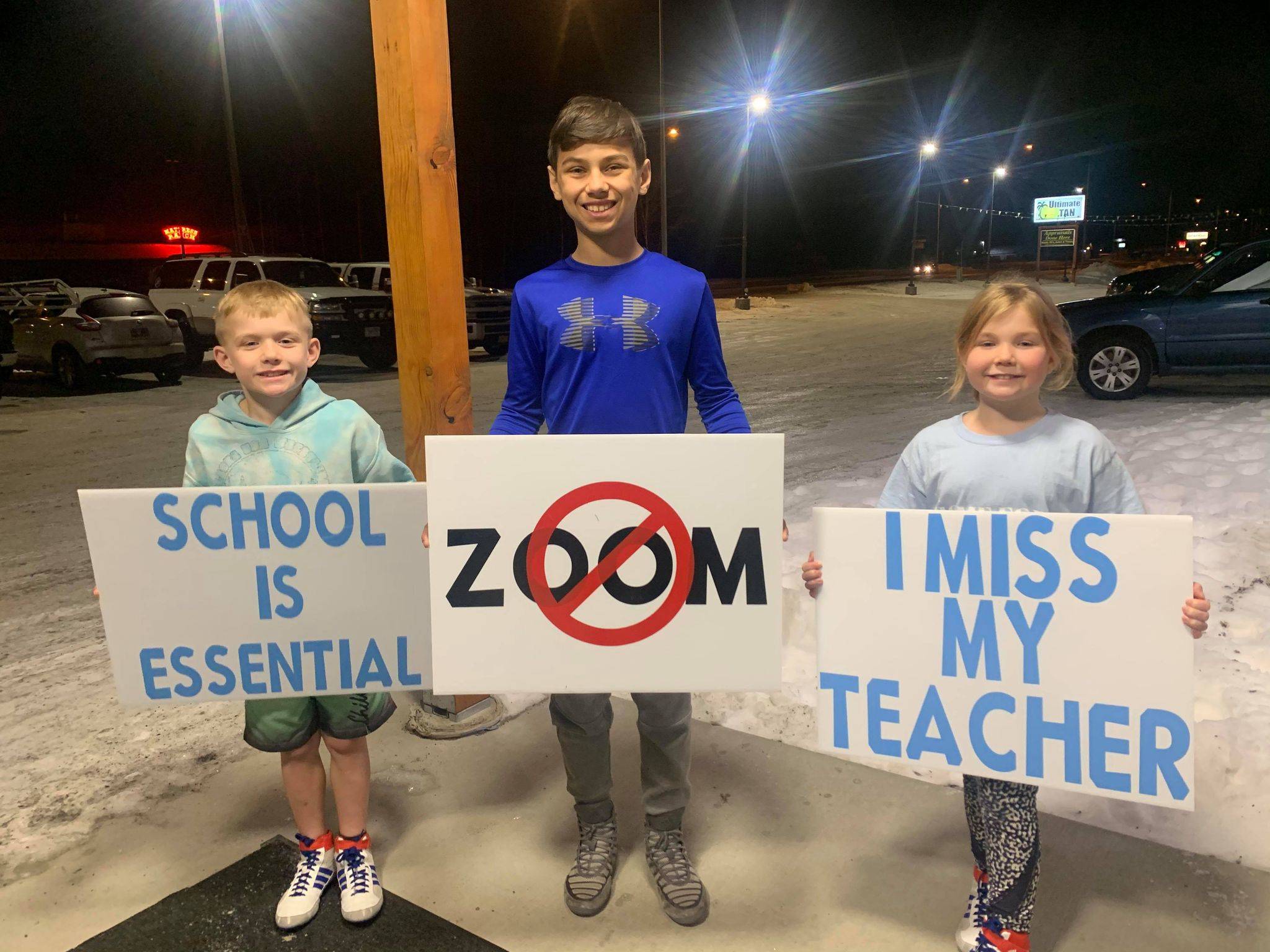 From left to right, Peyton Cobb, Mason Bock and Myla Cobb hold signs opposing remote learning on Monday, Dec. 14. (Courtesy Photo / Andie Bock)
