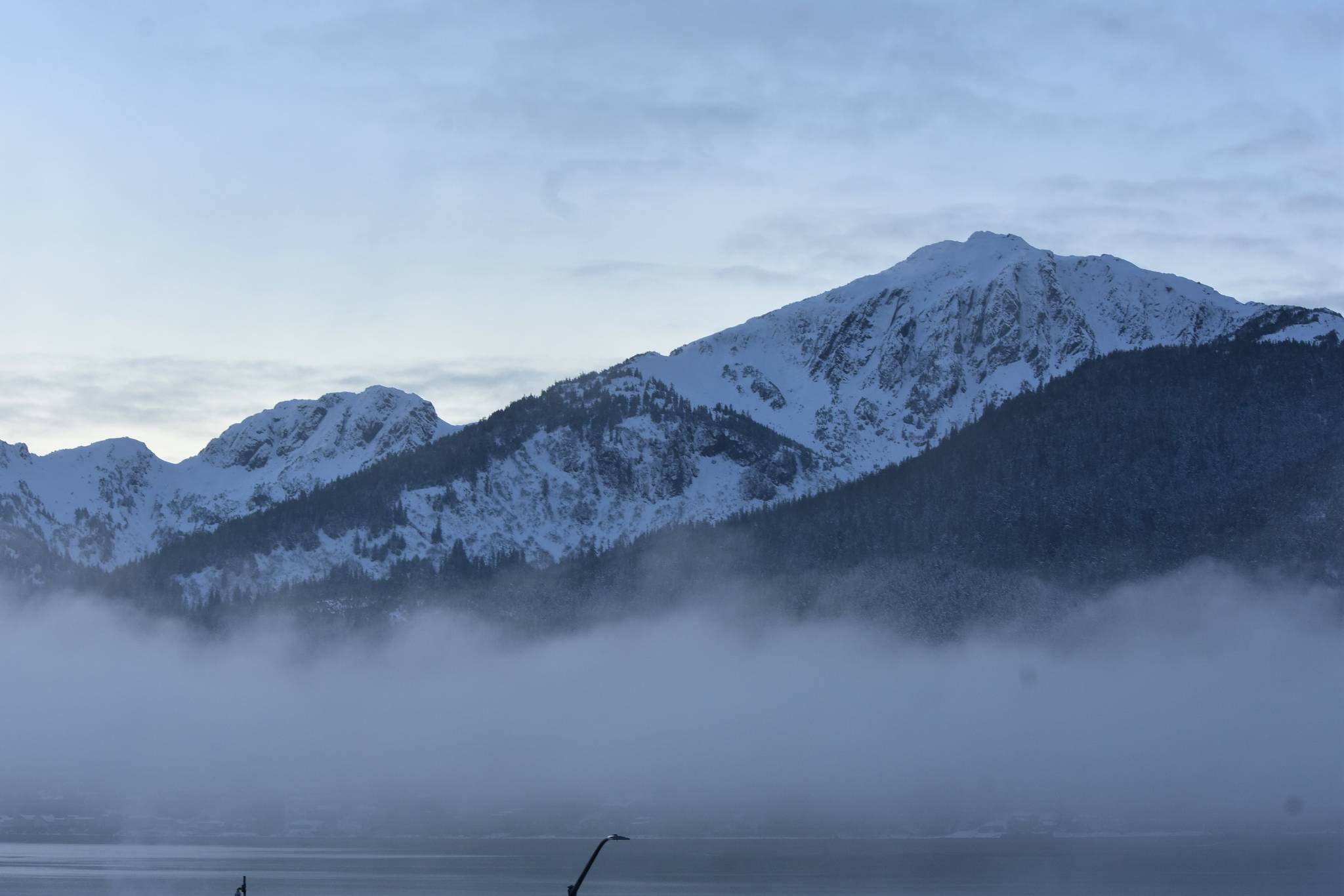 Douglas Island, part of the Tongass National Forest, breaks through the fog on Dec. 15, 2020.  A federal investigation found the U.S. Forest Service violated federal law in 2018 when it appropriated a $2 million grant to Alaska for input on Roadless Rule changes. (Peter Segall / Juneau Empire)