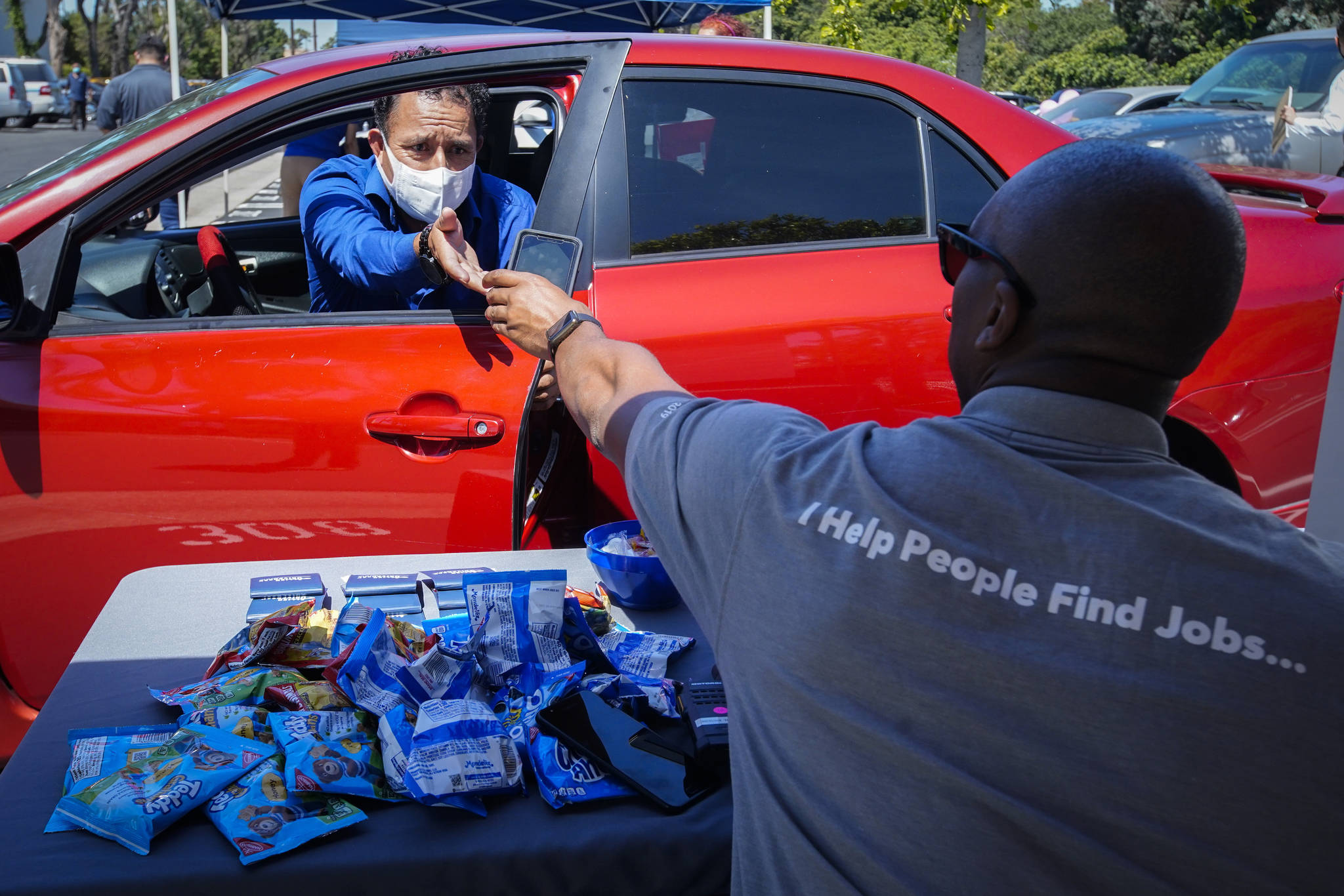 Brandon Earl, right, helps David Lenus, a job seeker, fill out an application at a drive up job fair for Allied Universal during the coronavirus pandemic, in Gardena, Calif. Coronavirus restrictions in California have put millions of people out of work, increasing the states unemployment rate earlier this year to levels not seen since the Great Depression. (AP Photo / Chris Carlson)