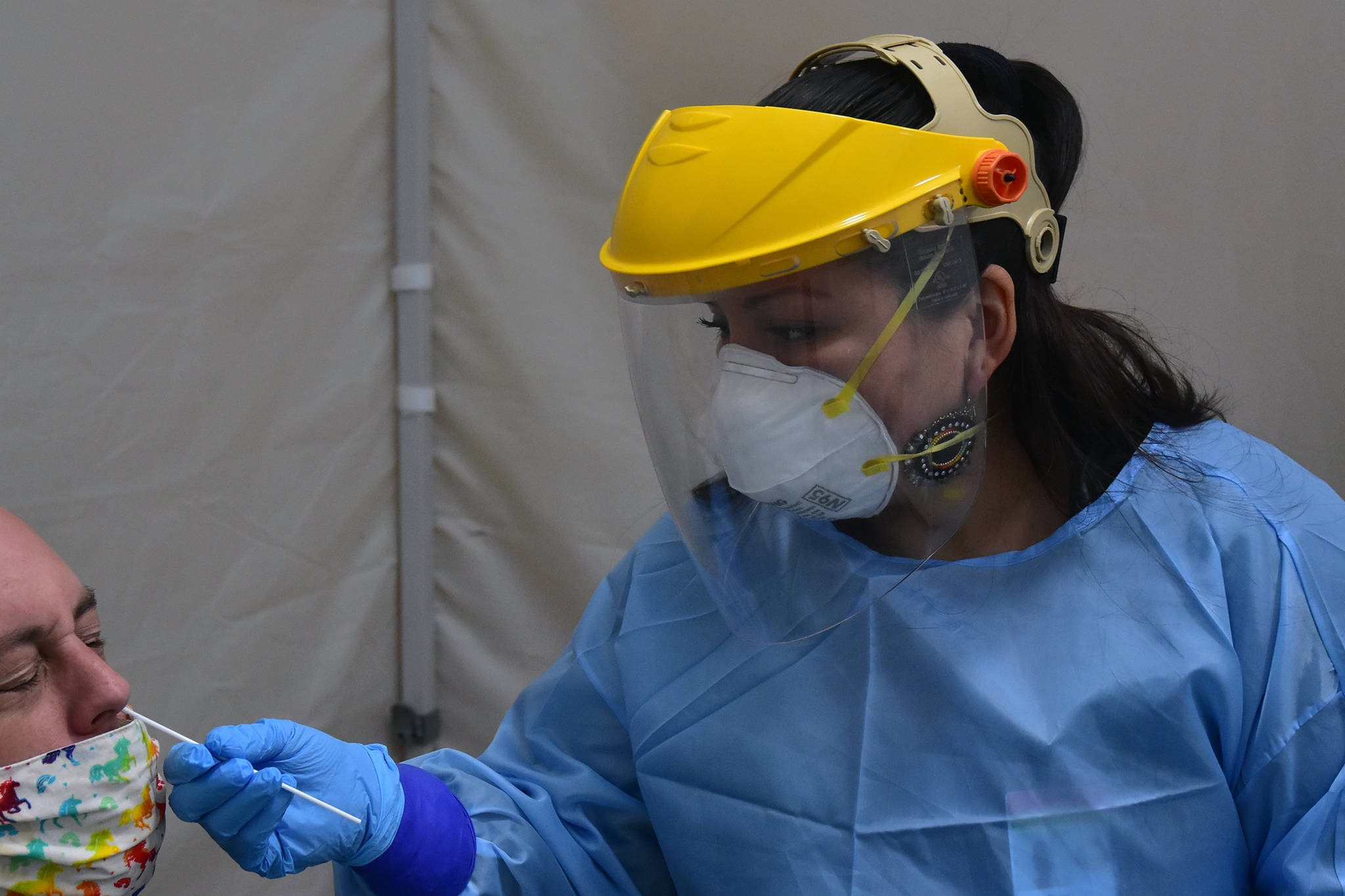 Emergency worker Melanie Chavez takes a sample from a man at Juneau International Airport in October. Airport-based testing is expected to transition to a vendor being secured by the state in late January. (Peter Segall / Juneau Empire File)