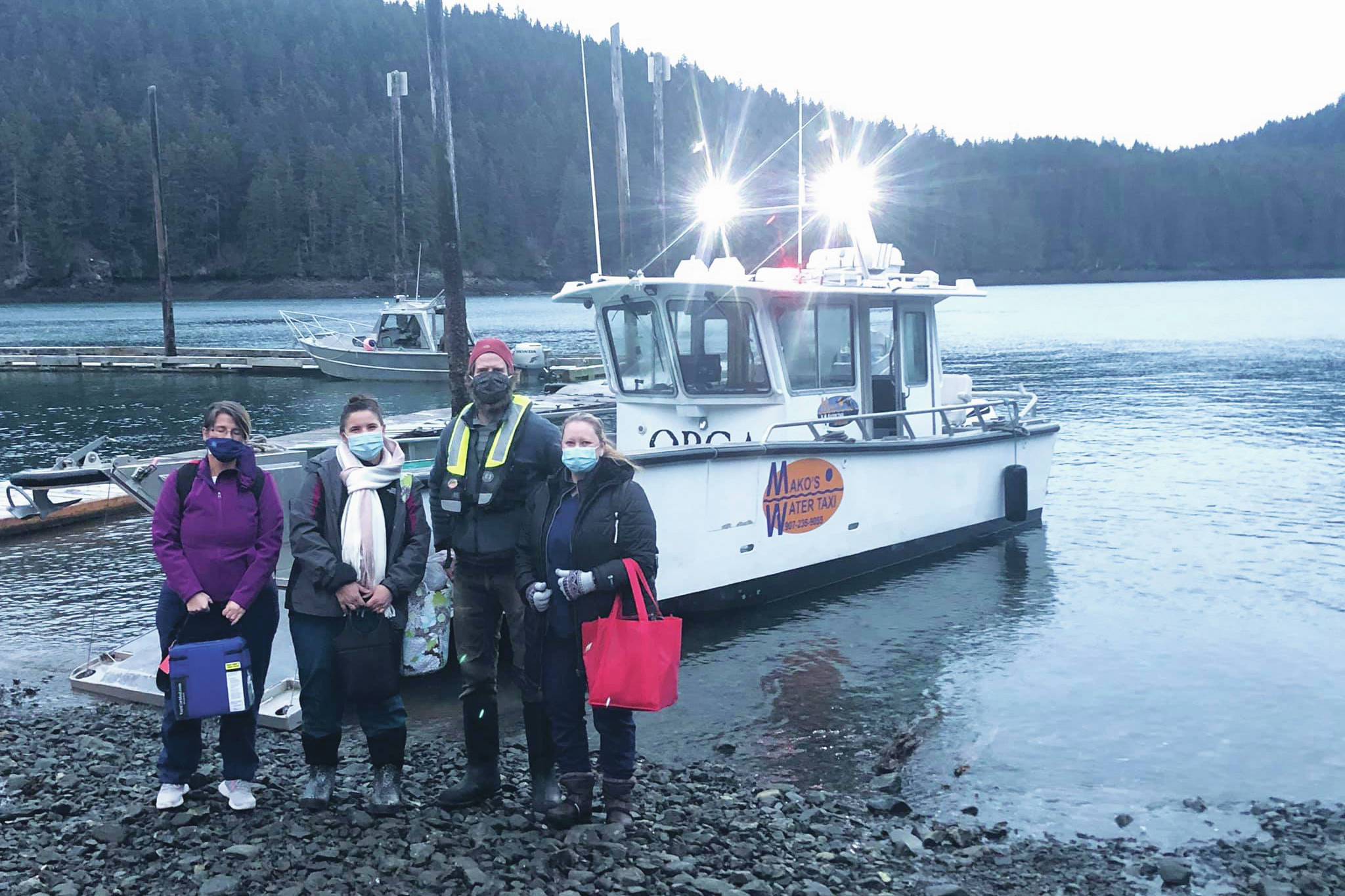 Curtis Jackson, second from right, poses on Thursday, Dec. 17, 2020, with SVT Heath & Wellness Center health care workers in Jakolof Bay, Alaska, after making a trip across Kachemak Bay from Homer to deliver the medical team and Pfizer COVID-19 vaccine. From left to right are nurse Candice Kreger, family nurse practitioner Kourtney Holder, Jackson, and family nurse practitioner Julie Drude. The health care workers then went by road to Seldovia. (Photo by Janel Harris courtesy of Mako's Water Taxi)