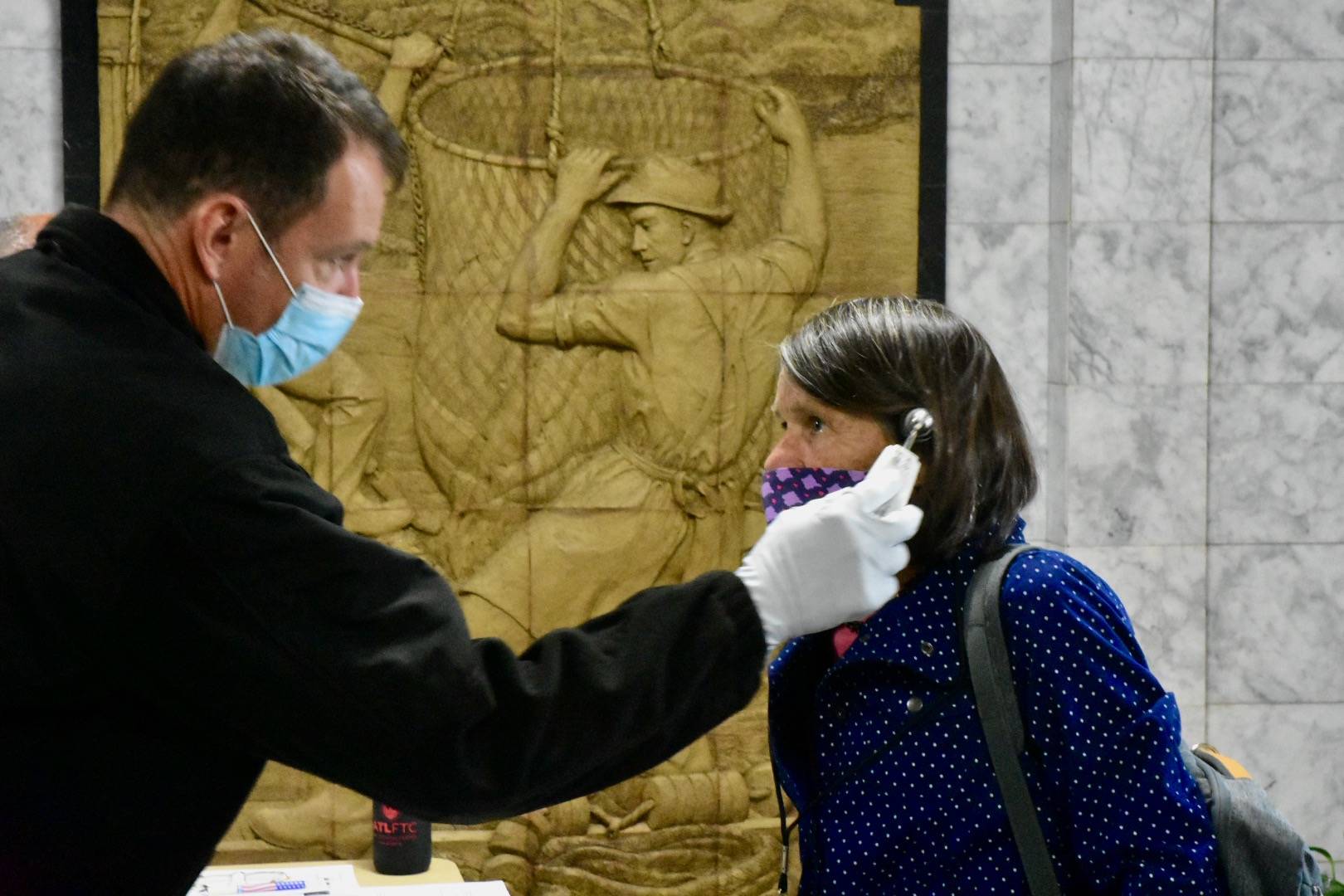Rep. Jennifer Johnston, R-Anchorage, gets her temperature taken as she enters the Alaska State Capitol on Monday, May 18, 2020. New policies will require all staff and legislators to wear masks in chambers. (Peter Segall / Juneau Empire File)
