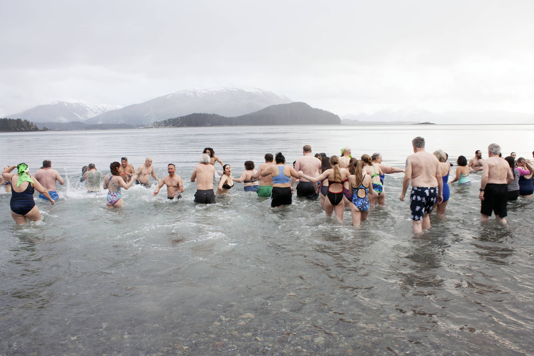 Polar Bear Dip participants make a mad dash Wednesday, Jan. 1, 2020, into the cold water at Auke Bay Recreation Area. This year’s dip is cancelled due to pandemic concerns. (Ben Hohenstatt / Juneau Empire File)