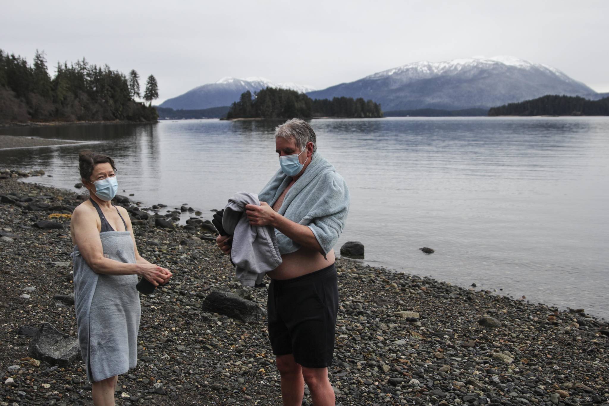 Sherri McDonald and Reid Tippets dry off after their annual dip in the water at Auke Recreation Picnic Area on New Years Day, Jan. 1, 2021. Tippets said he’d done the dip for 11 years in a row. The Polar Bear Dip, held for 30 years at Auke Rec, was canceled this year over pandemic concerns, but some individual households opted to make the dip with their families, with masks, distancing, and care very much in evidence, while other pods had fires or walked dogs next to the cold ocean. (Michael S. Lockett / Juneau Empire)
